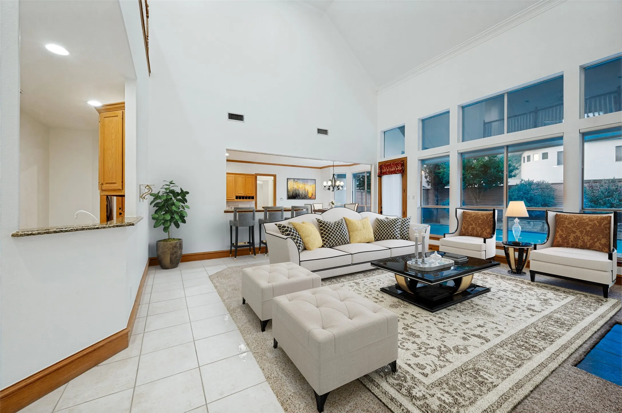 Grand family room boasting cascading floor-to-ceiling windows, soaring ceilings, and a seamless view of the sparkling pool oasis.