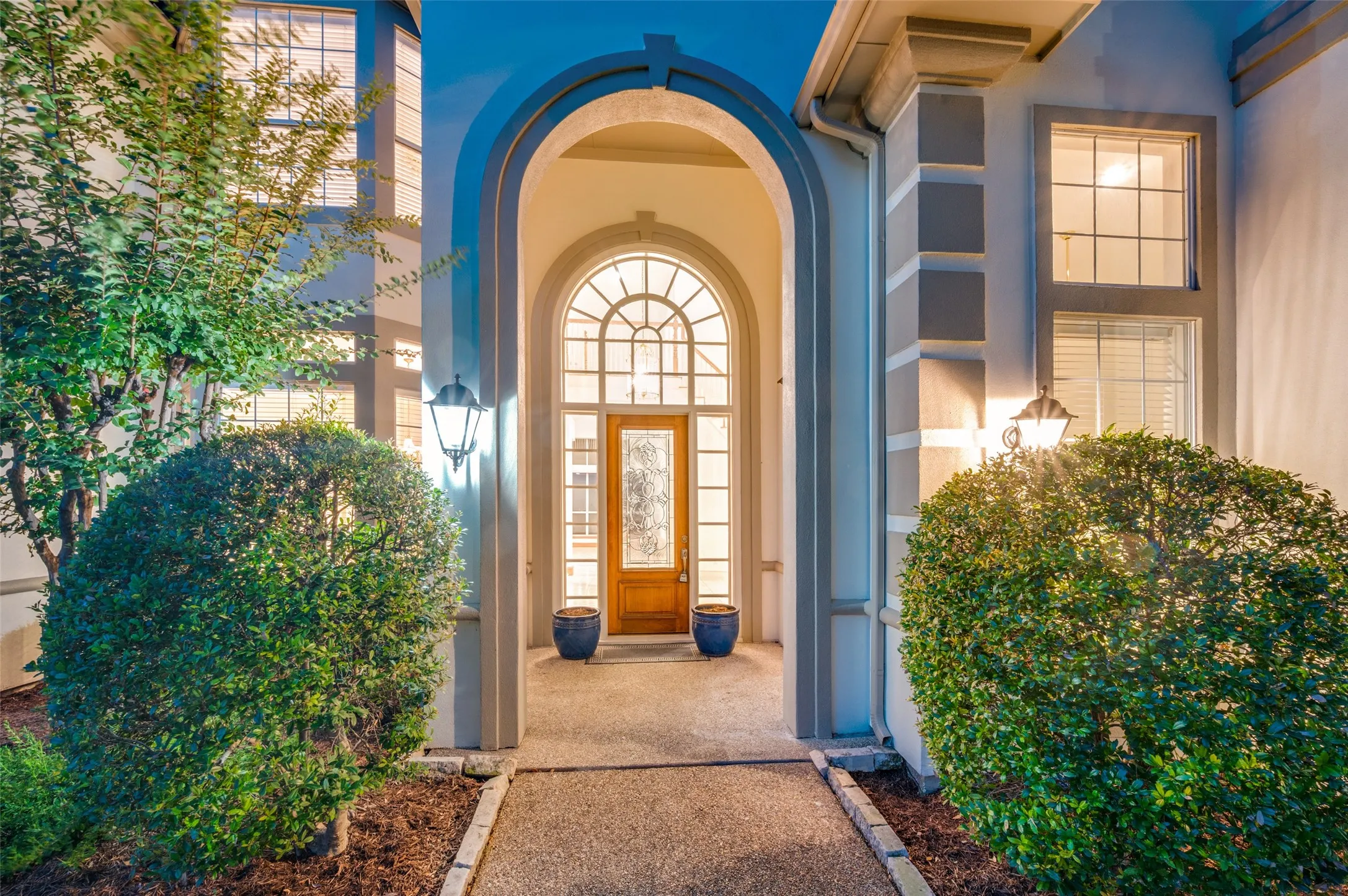 Arched entryway featuring a transom window, sidelights, and a wood-panel door with decorative glass