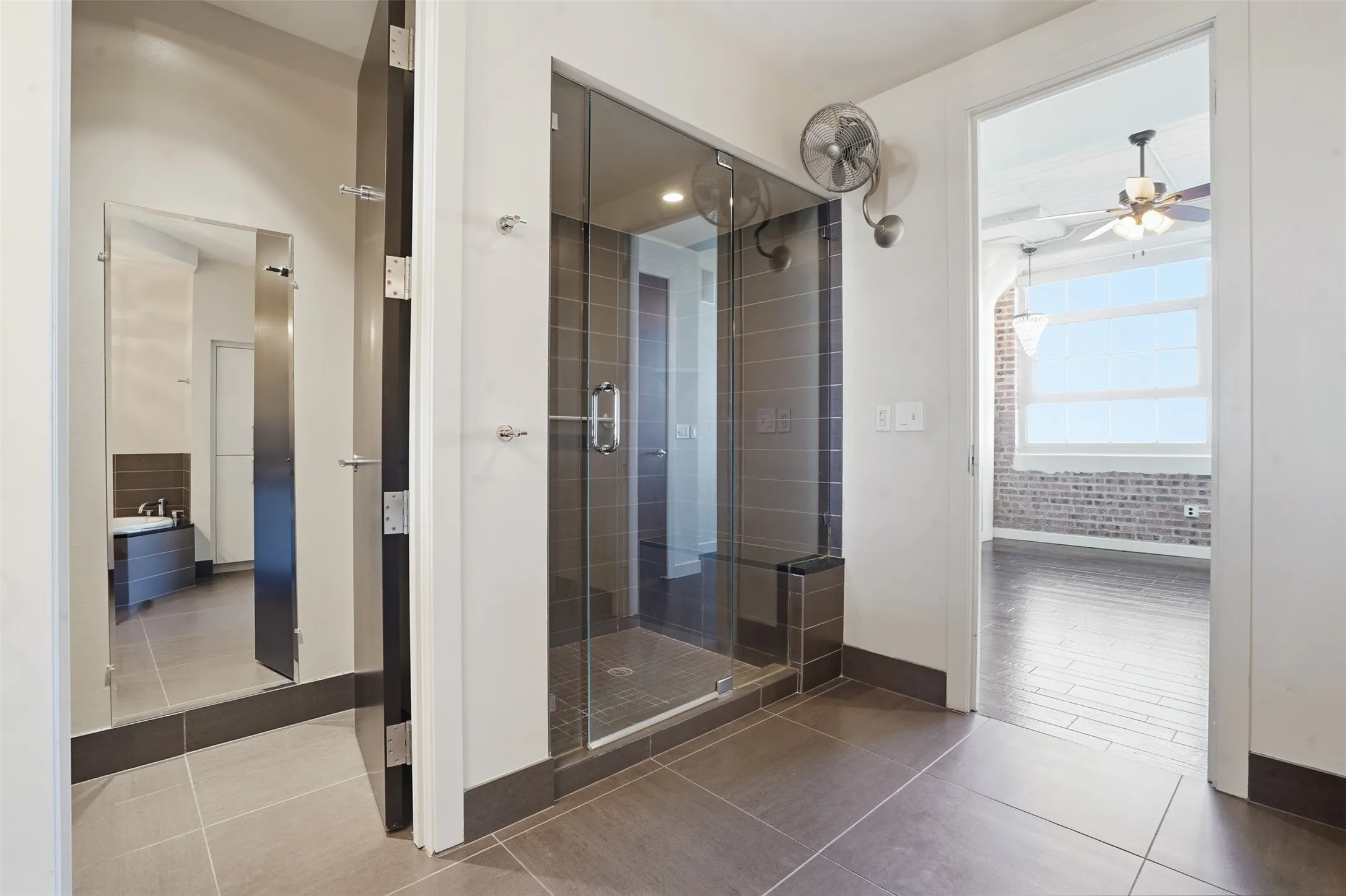 Glass-enclosed shower with dark tile surround and integrated bench
