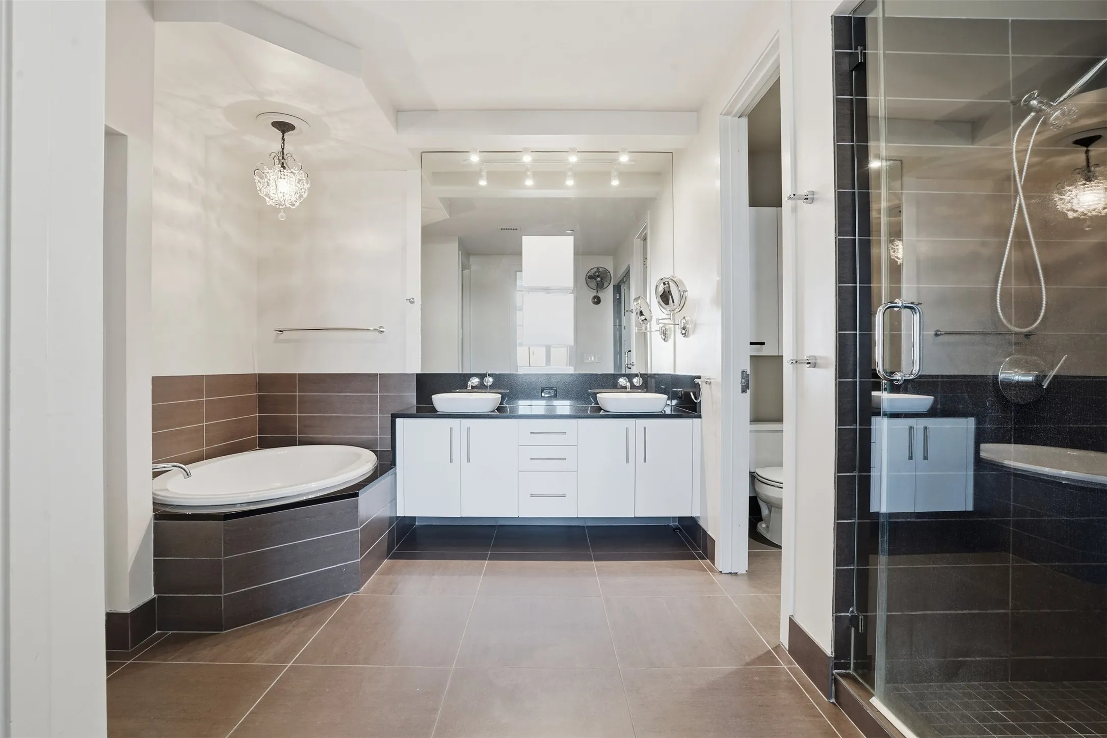 Bathroom featuring a glass-enclosed shower, a built-in soaking tub, and a dual vanity with vessel sinks