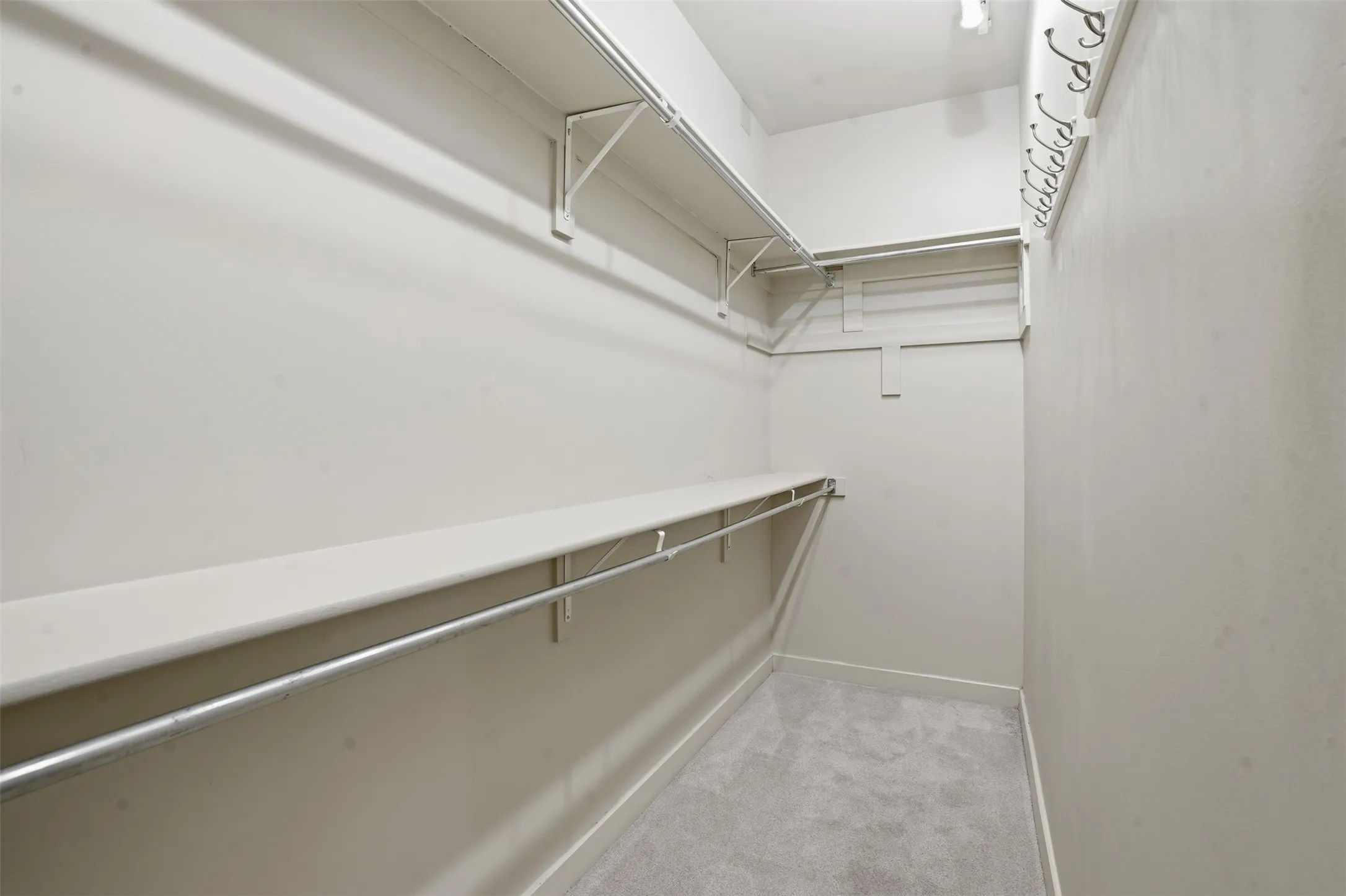 Walk-in closet featuring light-toned walls, gray carpet flooring, and white wire shelving