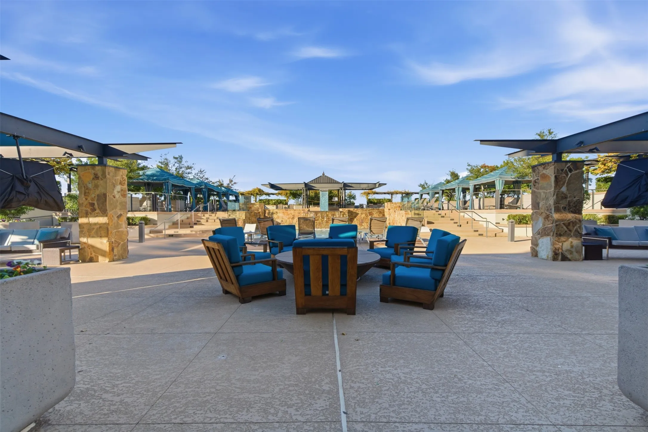 Spacious outdoor lounging area featuring a circular arrangement of wood-frame chairs with blue cushions