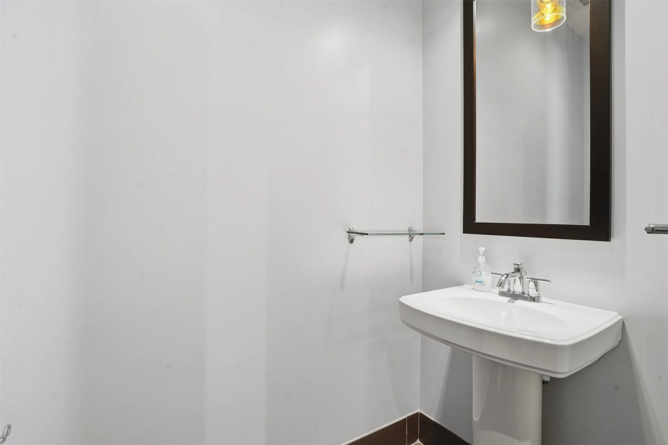 Pedestal sink with chrome faucet, framed mirror, and built-in wall shelving