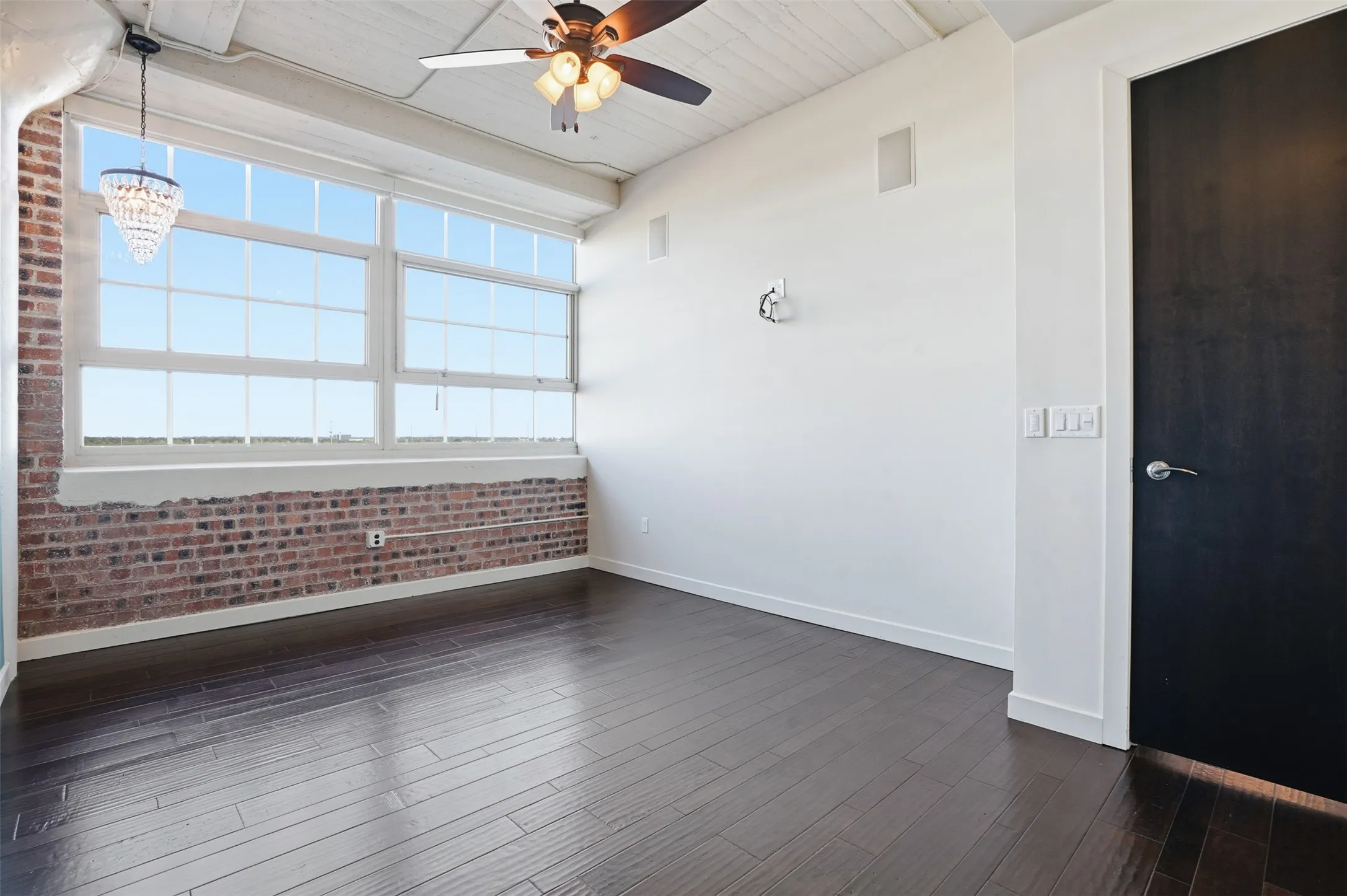 Expansive windows showcasing an exposed brick wall and dark wood-finish flooring