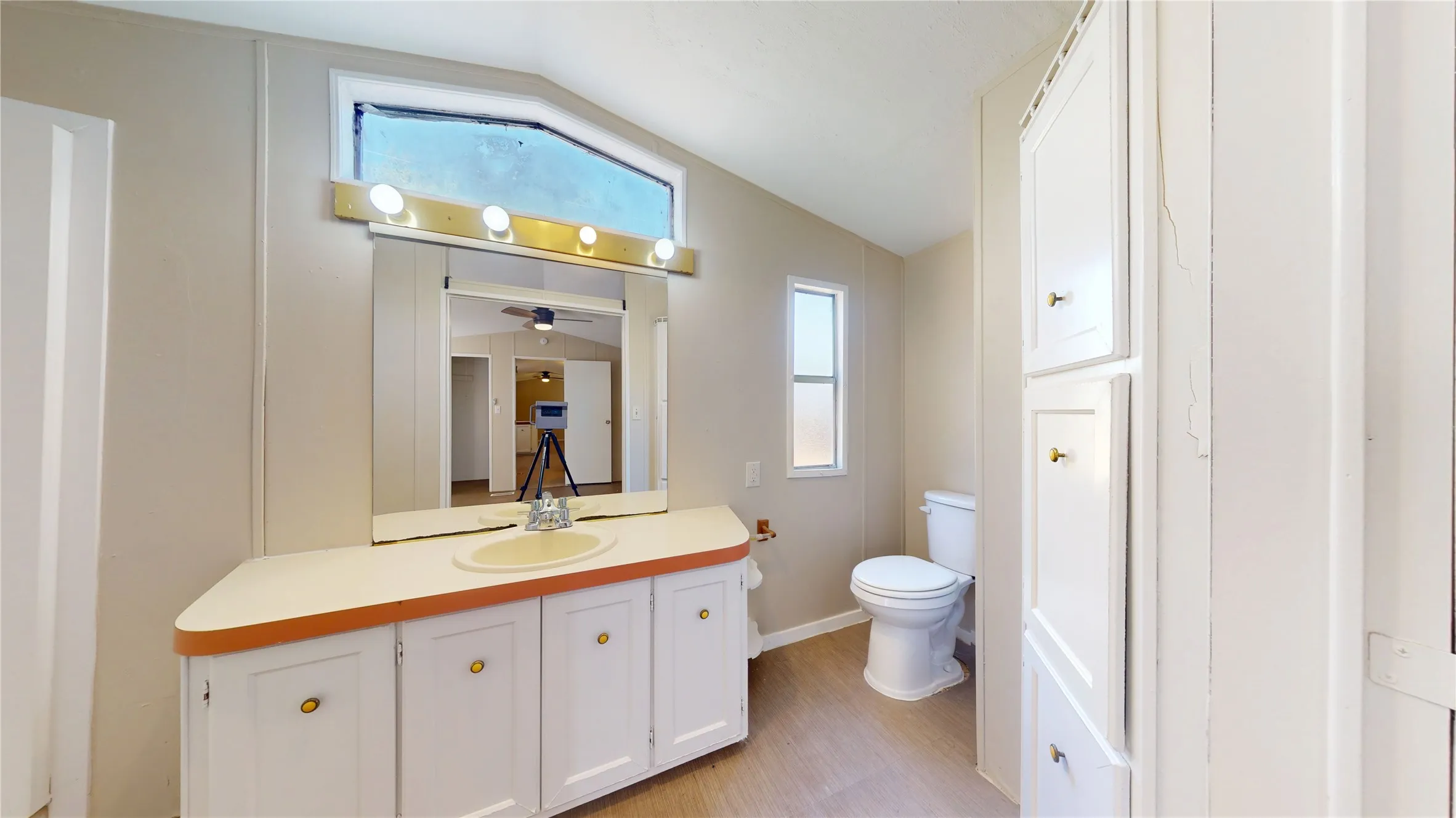Vanity with integrated sink, overhead lighting, wood-finish flooring, and built-in storage cabinetry