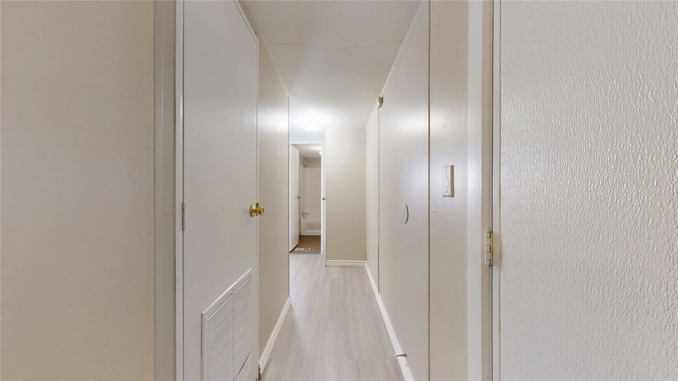 Hallway featuring wood-finish flooring, flush panel doors, and built-in storage