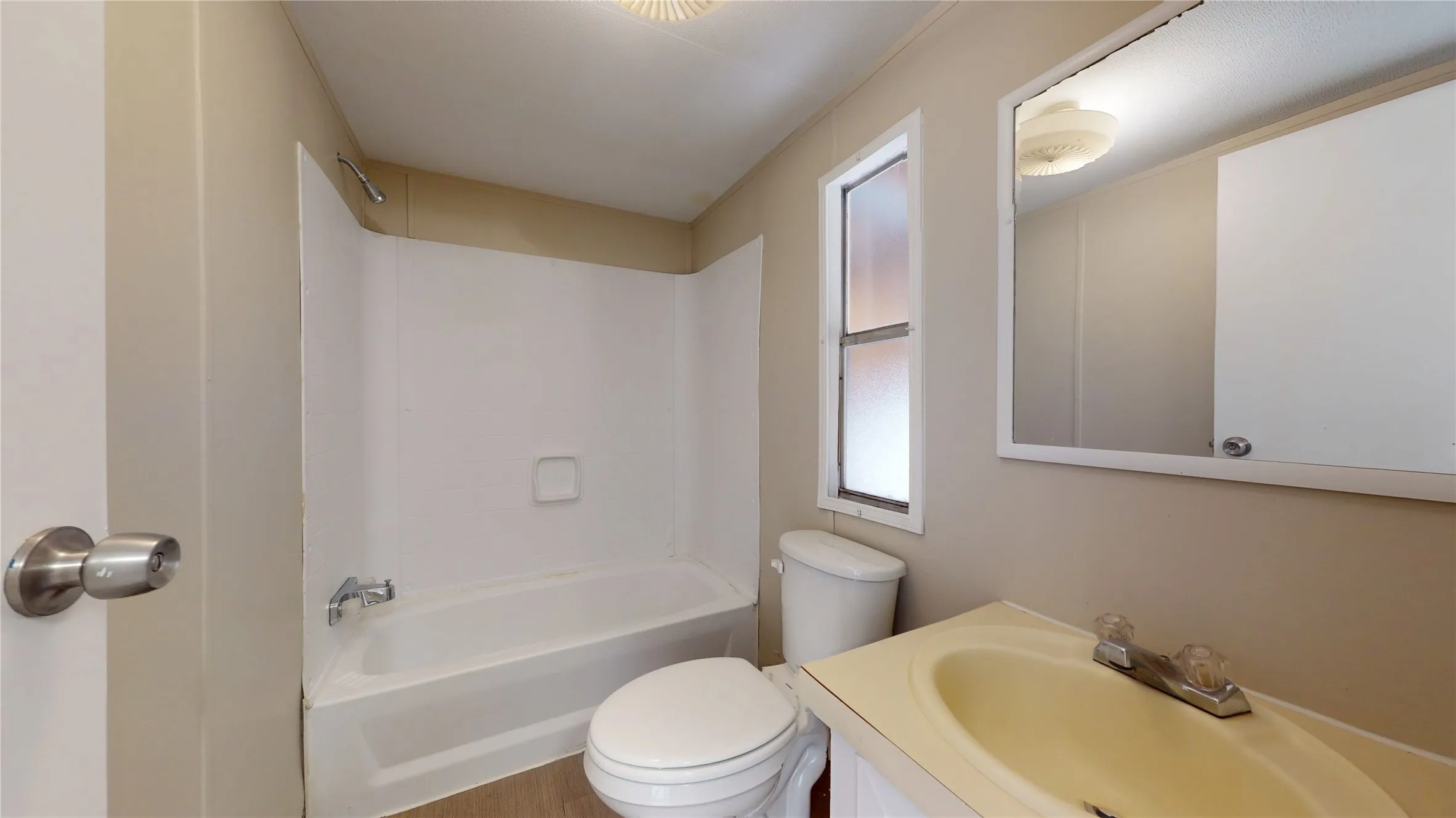 Bathroom featuring a white bathtub with shower surround, toilet, and vanity with an integrated sink