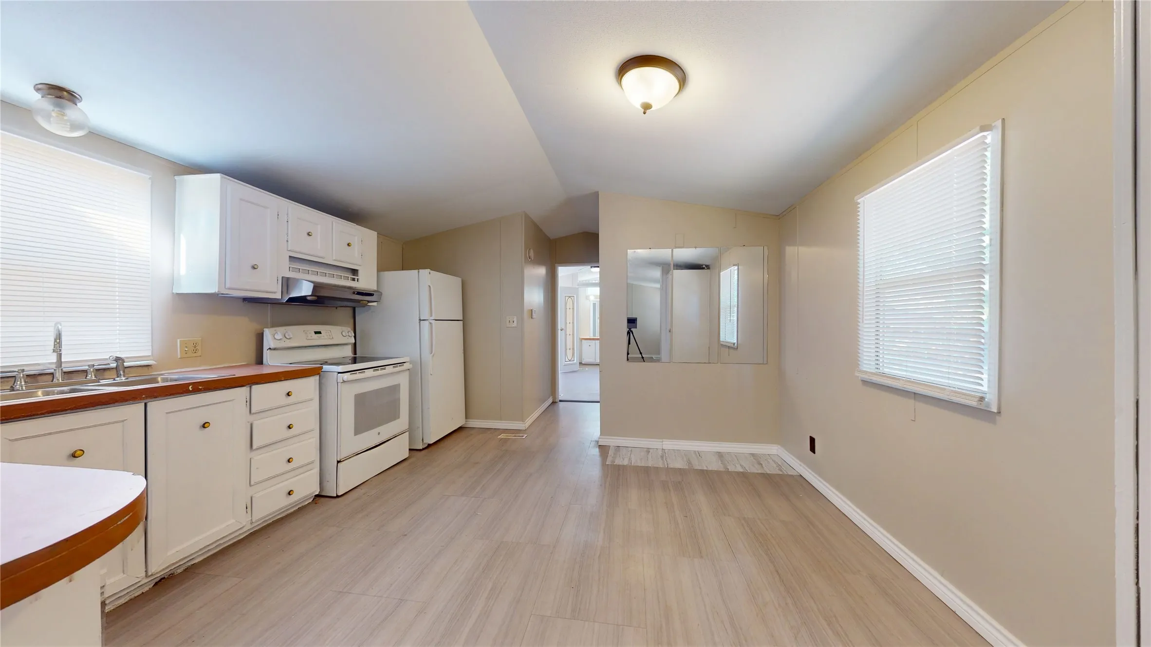 Kitchen featuring white cabinetry, a dual basin sink, white appliances, and wood-finish flooring