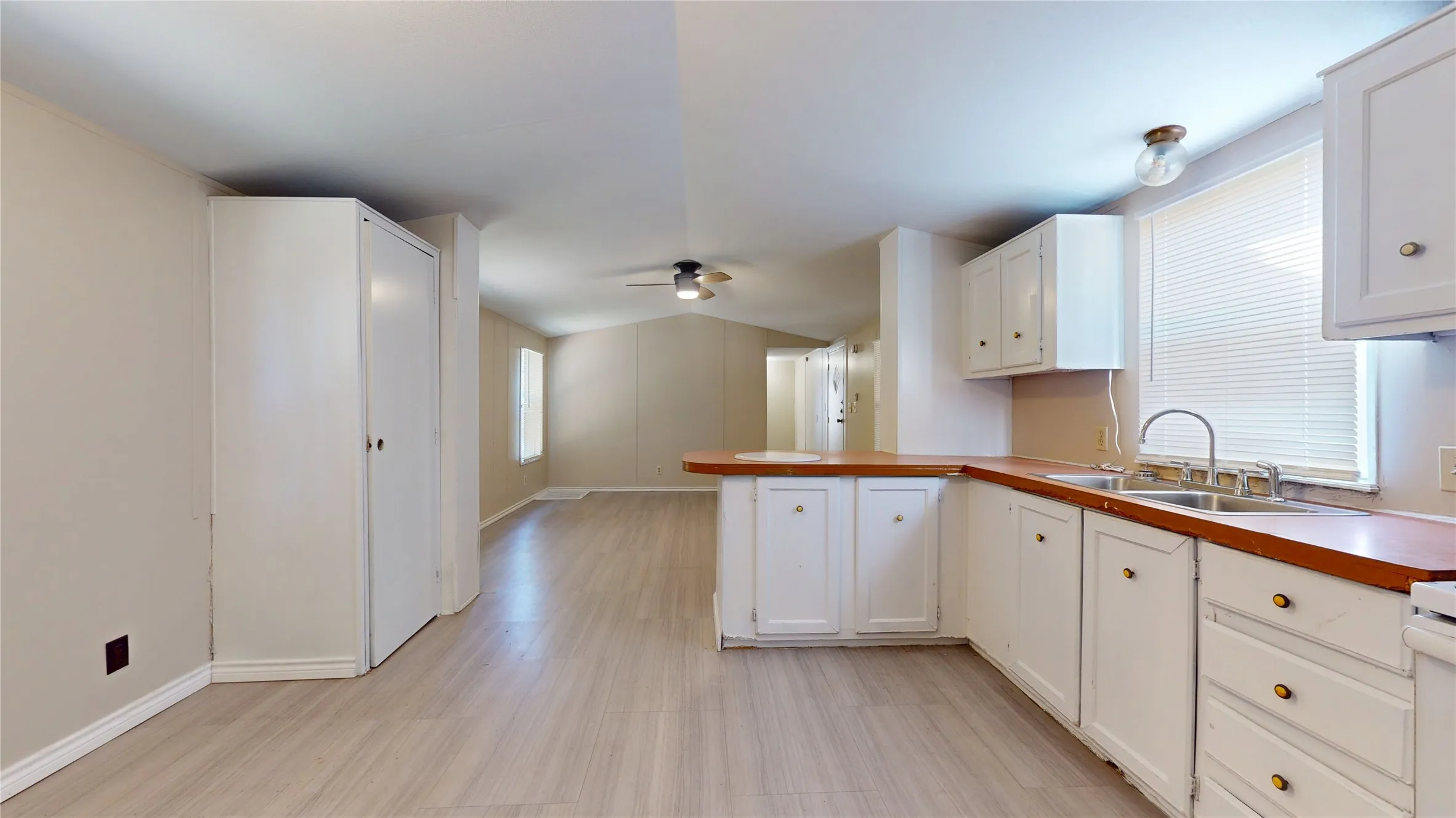 Kitchen featuring white cabinetry with brass-tone hardware, a stainless steel sink, and wood-finish countertops