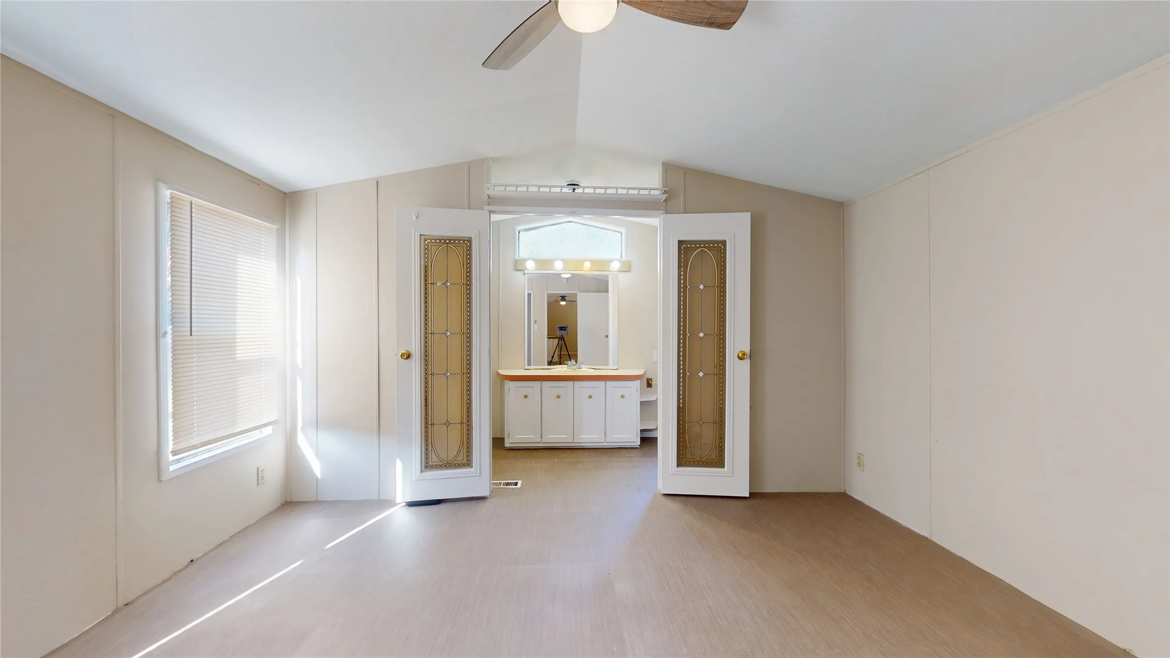 Vaulted ceiling with a ceiling fan, wood-finish flooring, and a large window with blinds