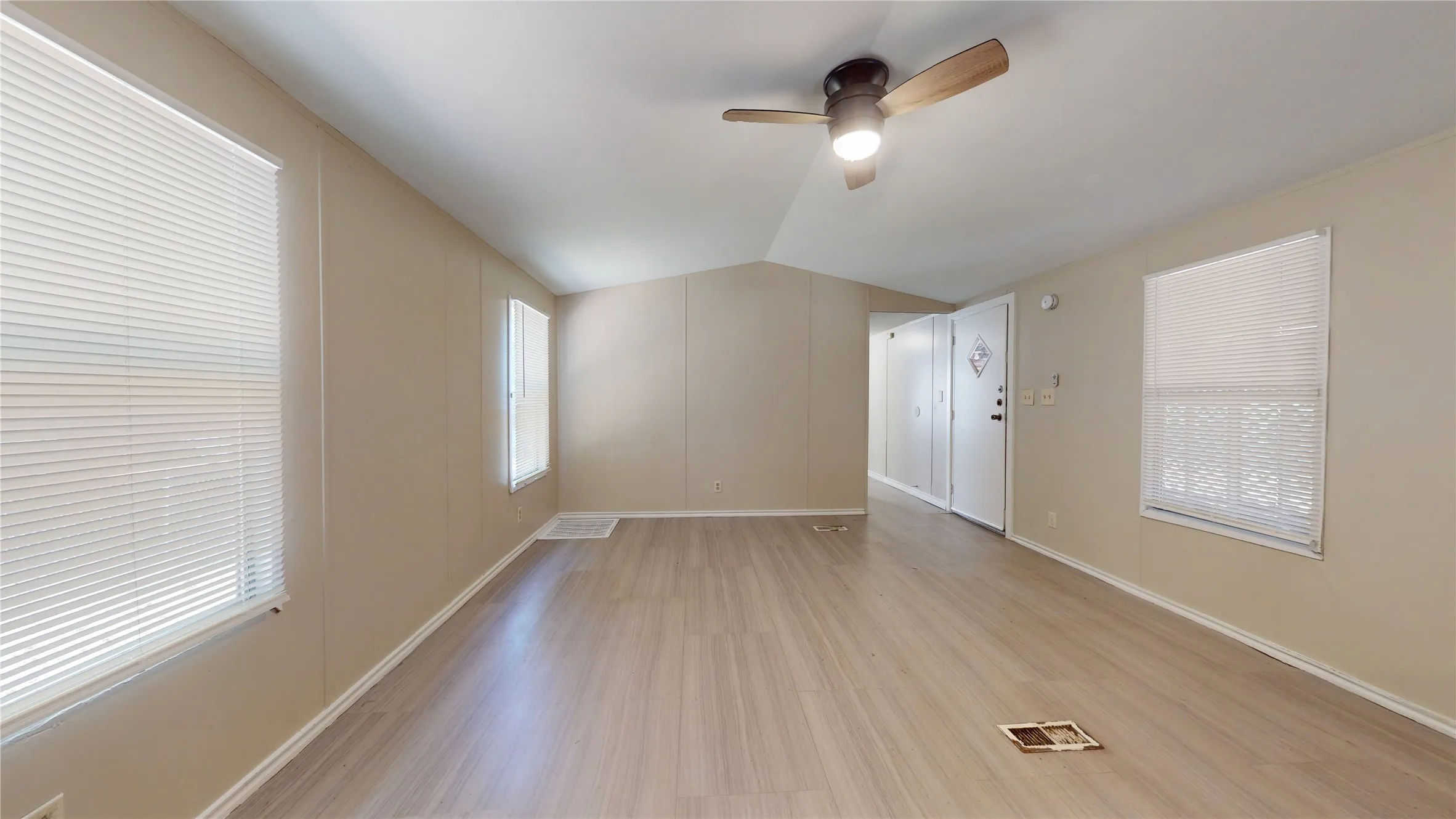Vaulted ceiling with a ceiling fan, wood-finish flooring, and multiple windows with blinds