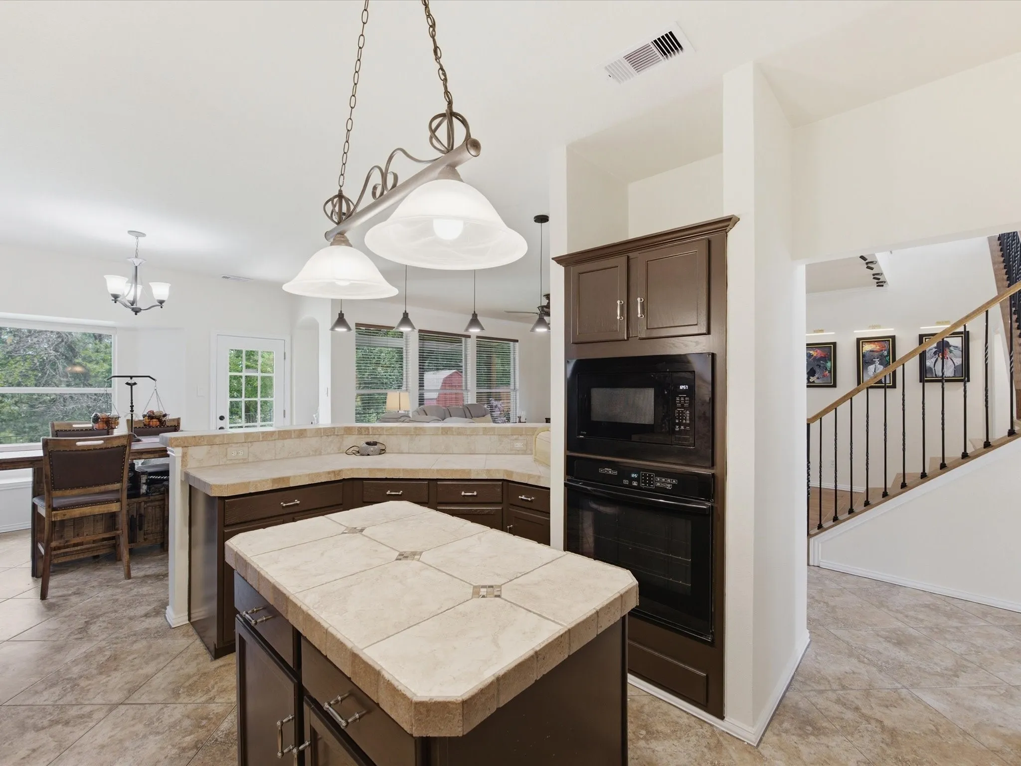 Kitchen featuring a tile-topped island, dark wood-finish cabinetry, and built-in black appliances