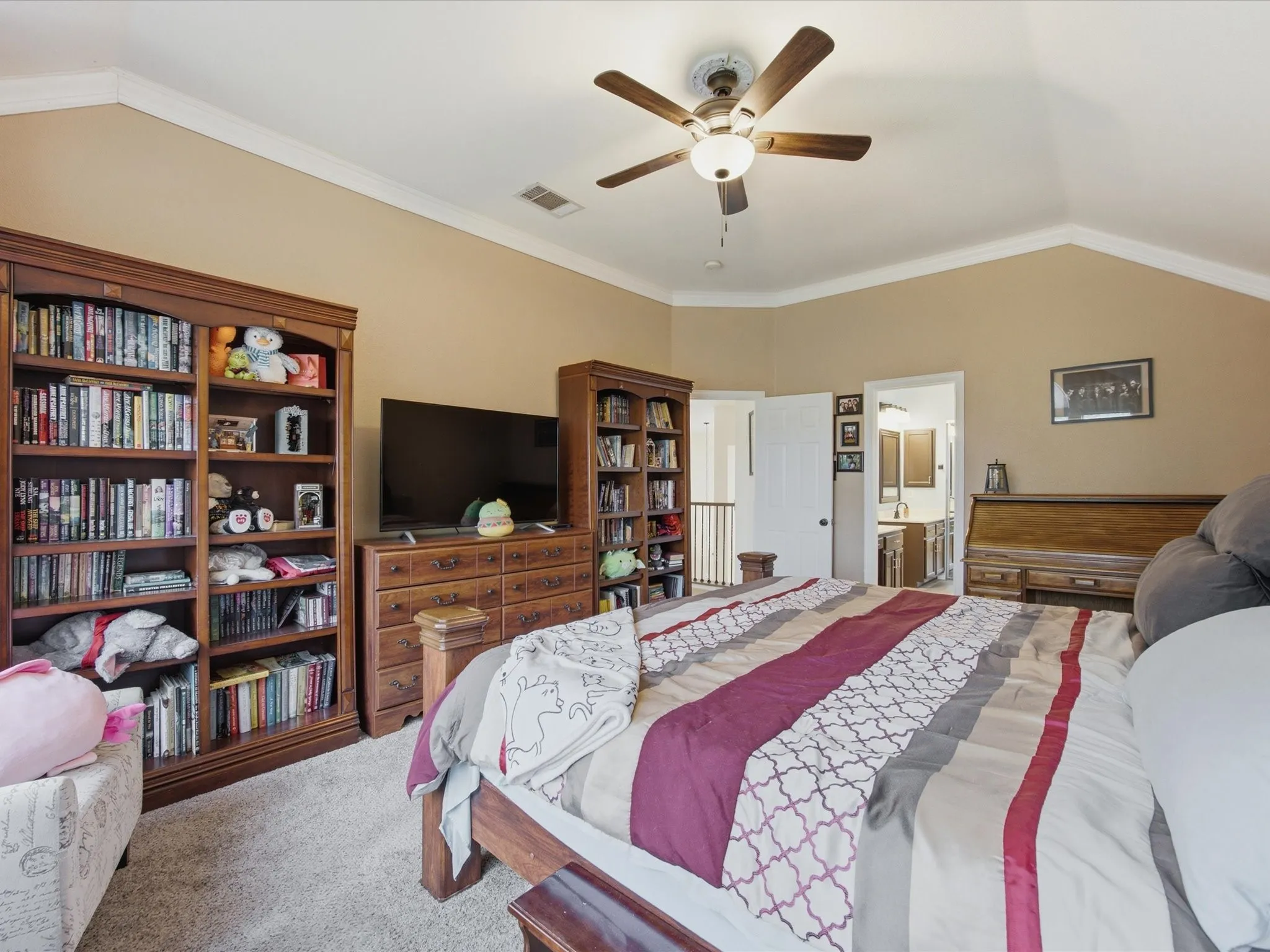Vaulted ceiling Primary bedroom with neutral wall tones and crown molding