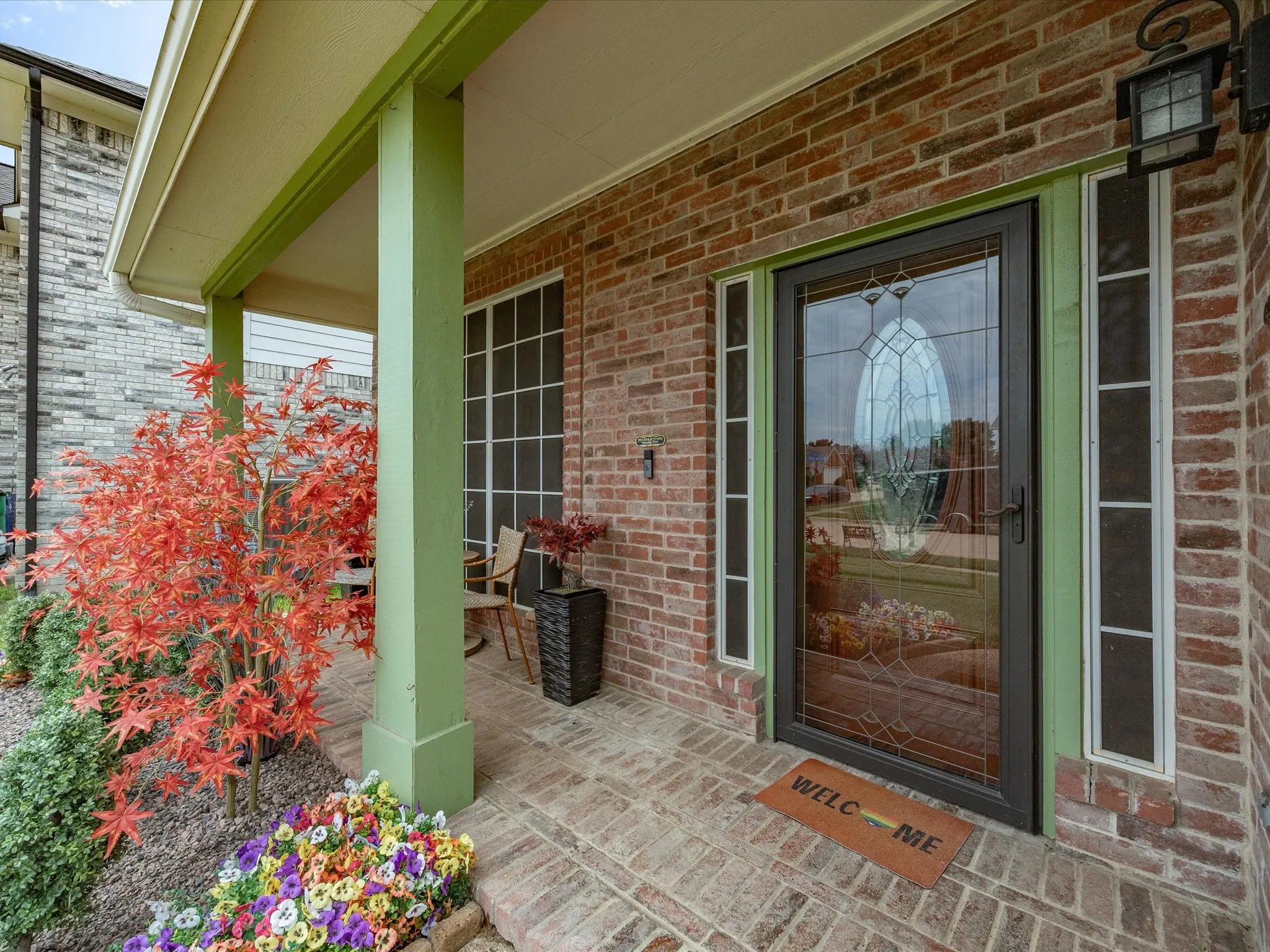 Brick facade entryway with a decorative glass front door, two sidelight windows, and an overhead transom window