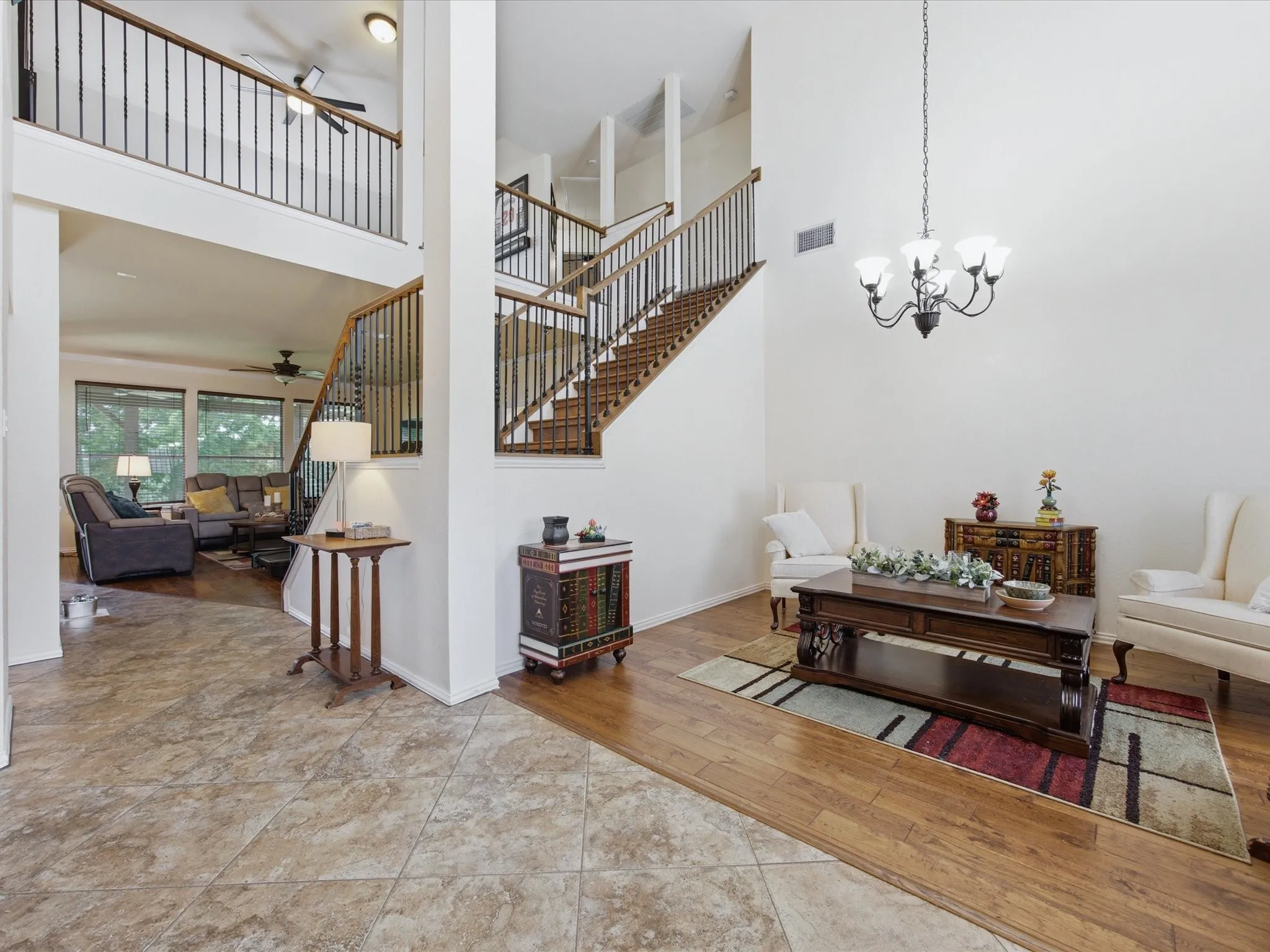 Two-story foyer featuring high ceilings, a wrought iron chandelier, wood-finish flooring, and a staircase with an open railing