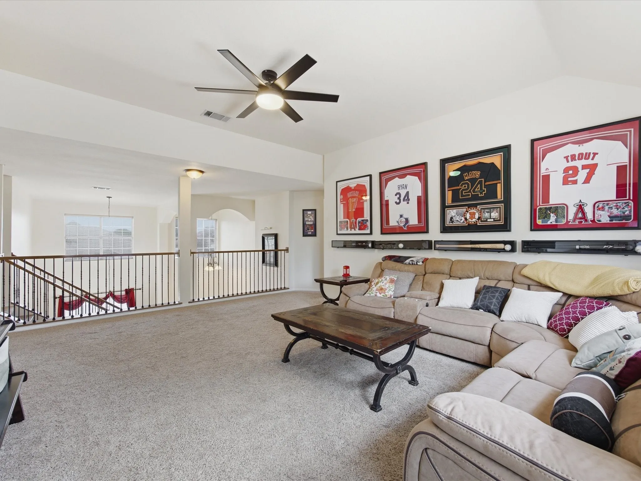 Open-concept living area featuring wood-finish flooring, a ceiling fan, and large windows with blinds