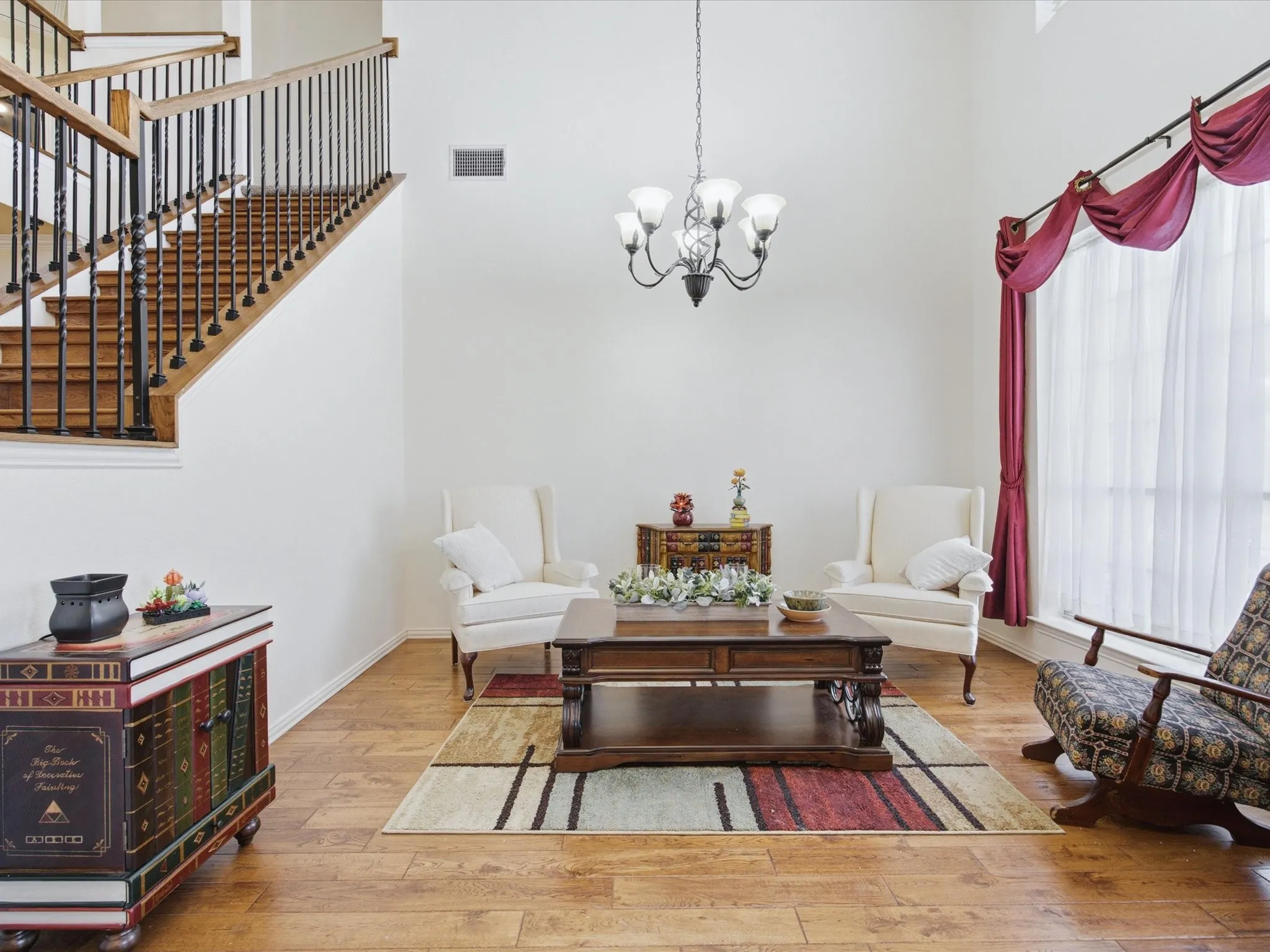 Two-story foyer featuring high ceilings, a wrought iron chandelier, wood-finish flooring, and a staircase with an open railing