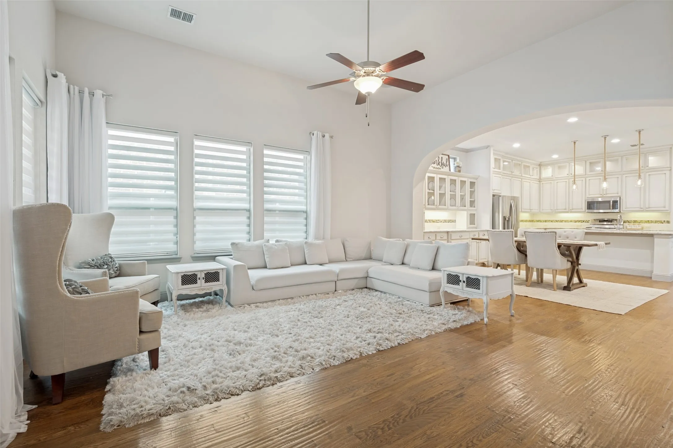 Hardwood-finish flooring throughout, featuring a vaulted ceiling and an arched entryway to the kitchen