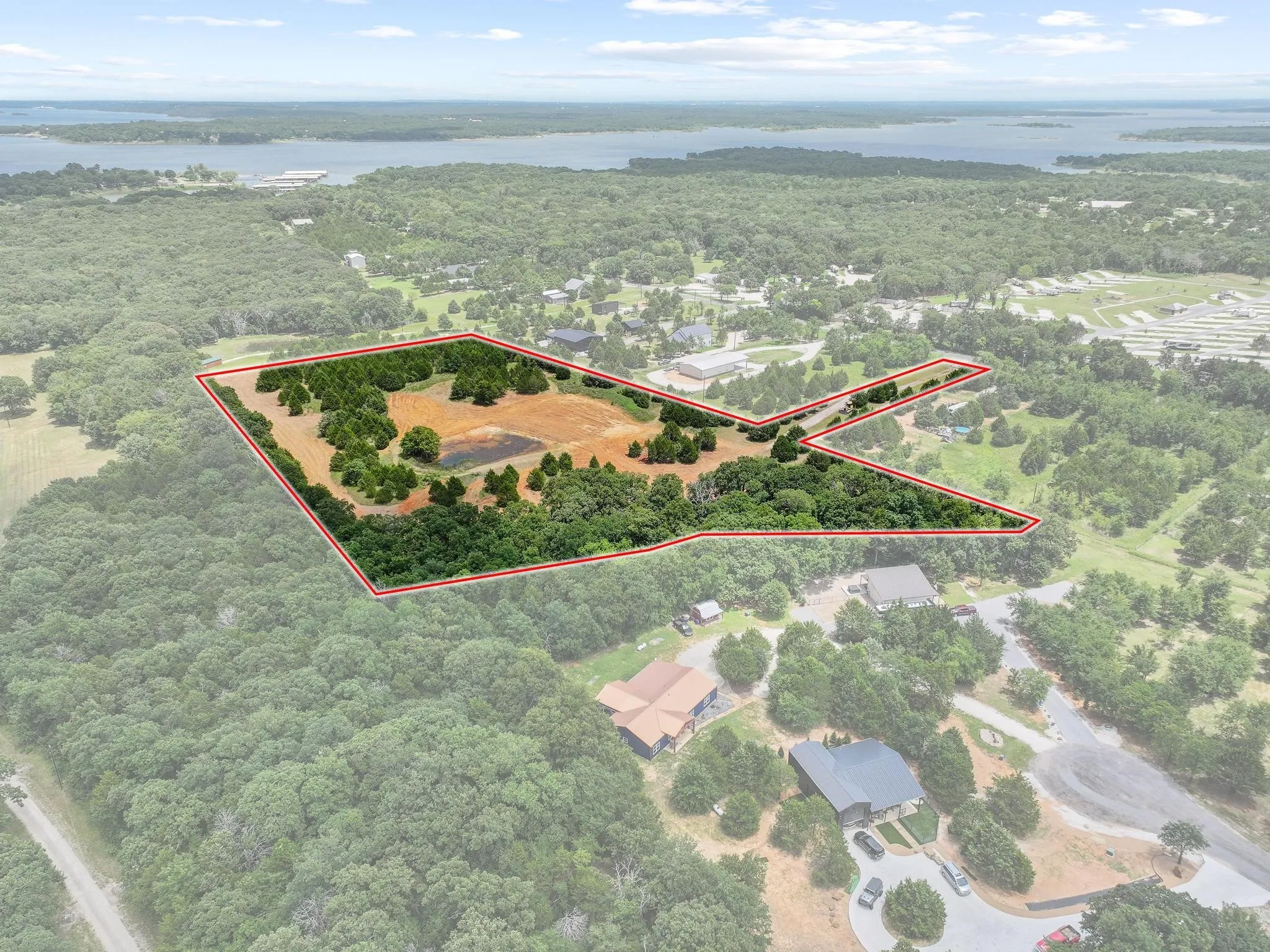 Expansive land parcel featuring a visible pond, mature trees, and open fields