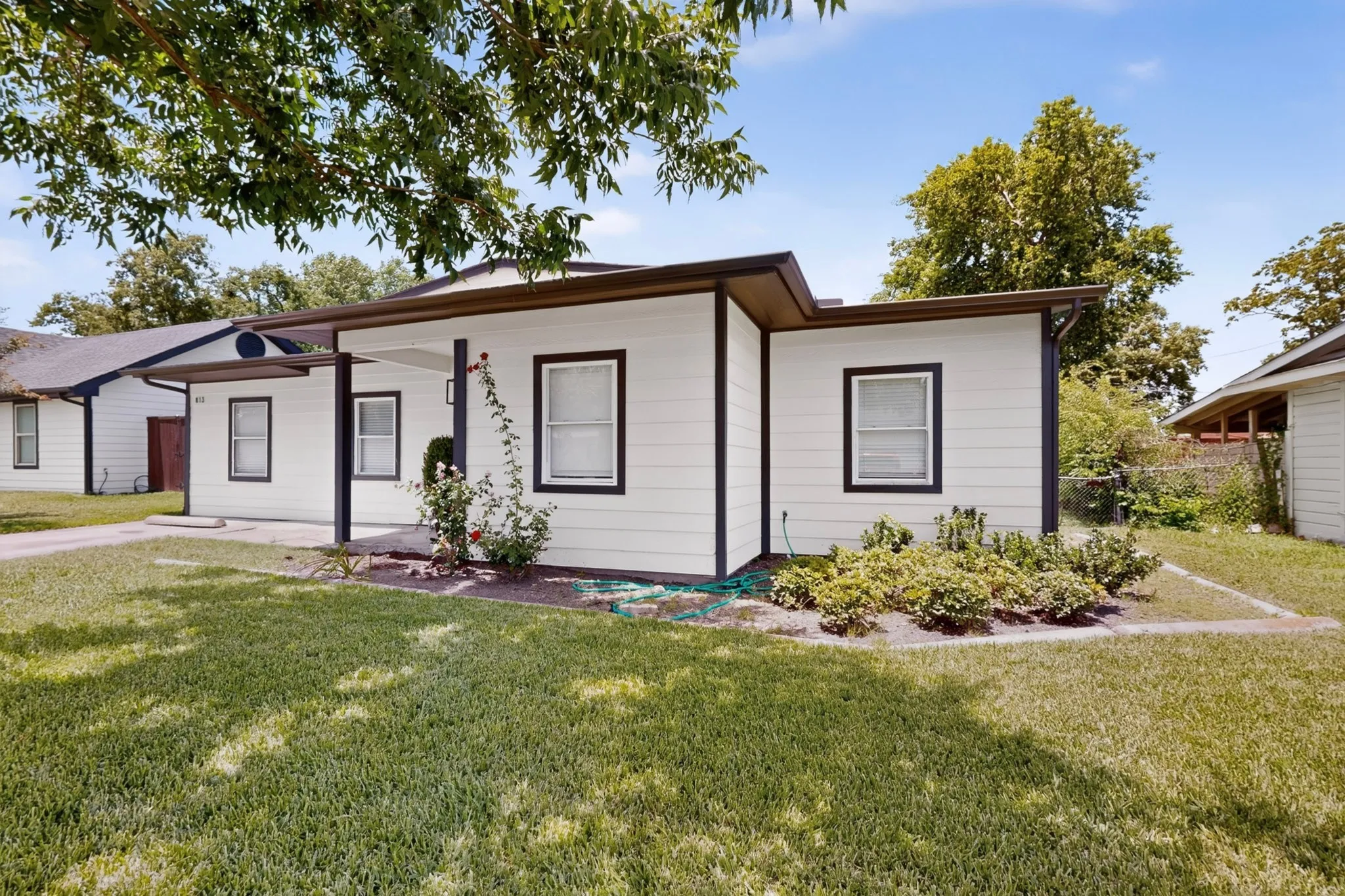 White siding exterior with dark trim and a covered front entry