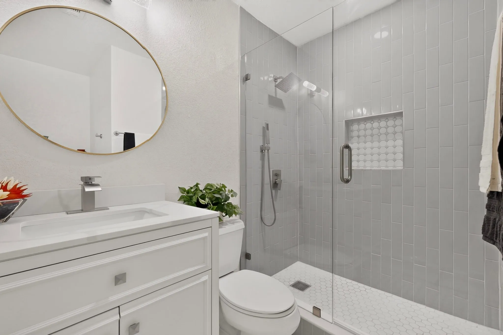 Contemporary bathroom featuring a frameless glass shower enclosure with vertical subway tile, a built-in shower niche with patterned tile, and a rainfall shower head