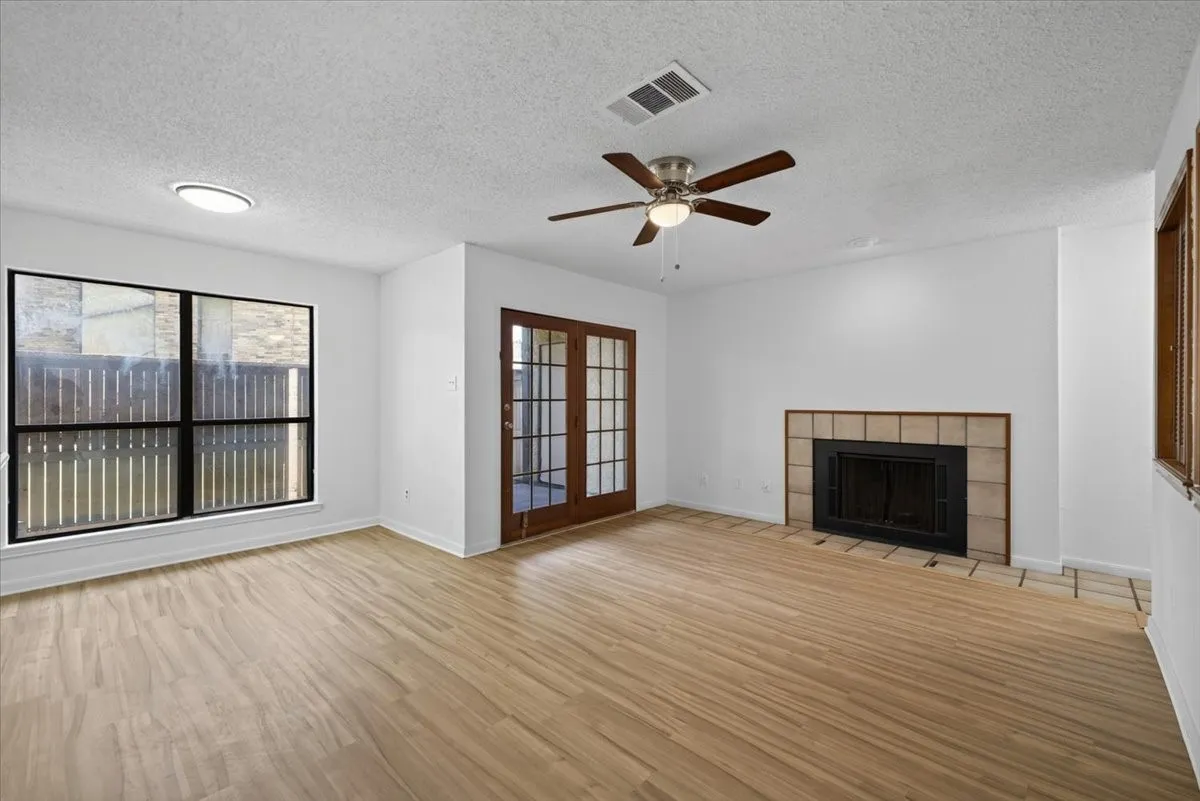 Spacious living-dining room featuring wood-finish flooring, a large window, and double French doors with glass panels