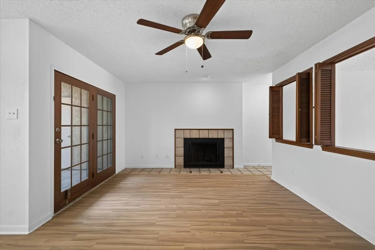 Living area featuring wood-finish flooring, a tile-surround fireplace, and a ceiling fan