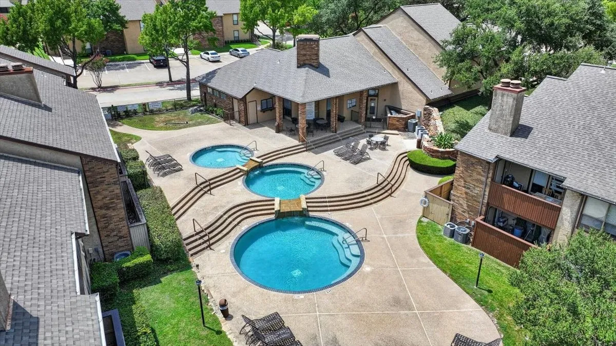 Central courtyard featuring three circular pools with integrated steps, concrete decking, and surrounding green spaces