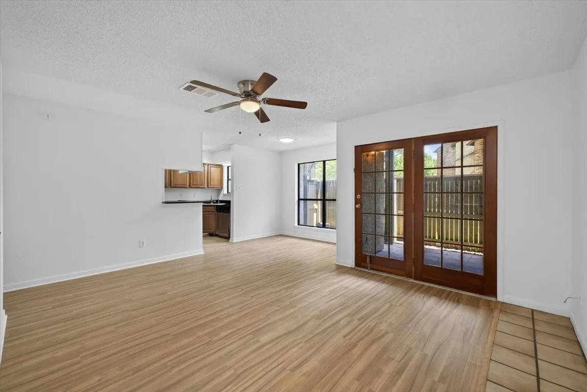 Spacious living area featuring wood-finish flooring, a ceiling fan, and white walls