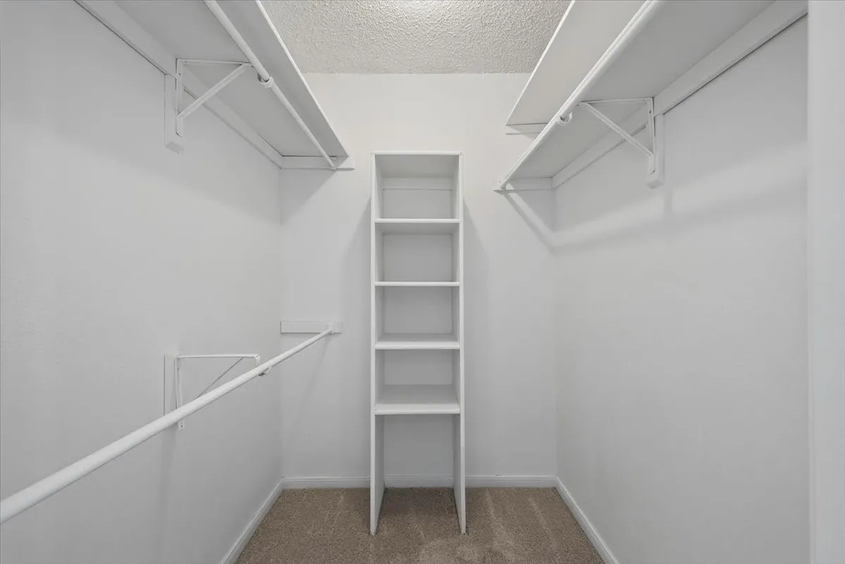 Walk-in closet featuring built-in shelving, white wire racks, and hanging rods