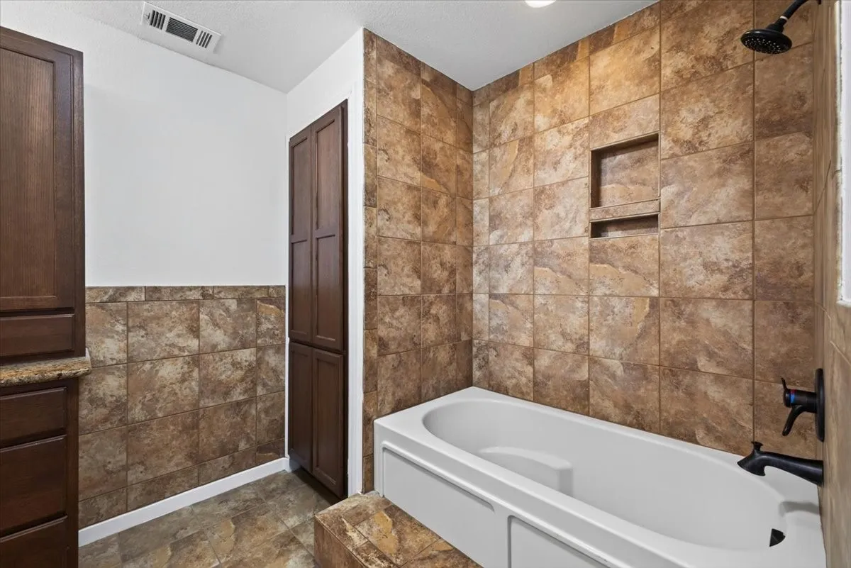 Bathroom featuring a shower-tub combination with tile surround and built-in niche