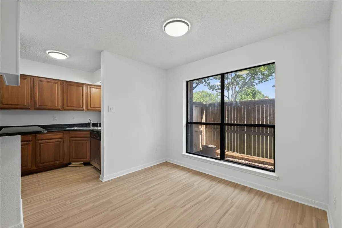 Dining area featuring wood-finish flooring, with modern lighting, and a pass-through opening to the kitchen