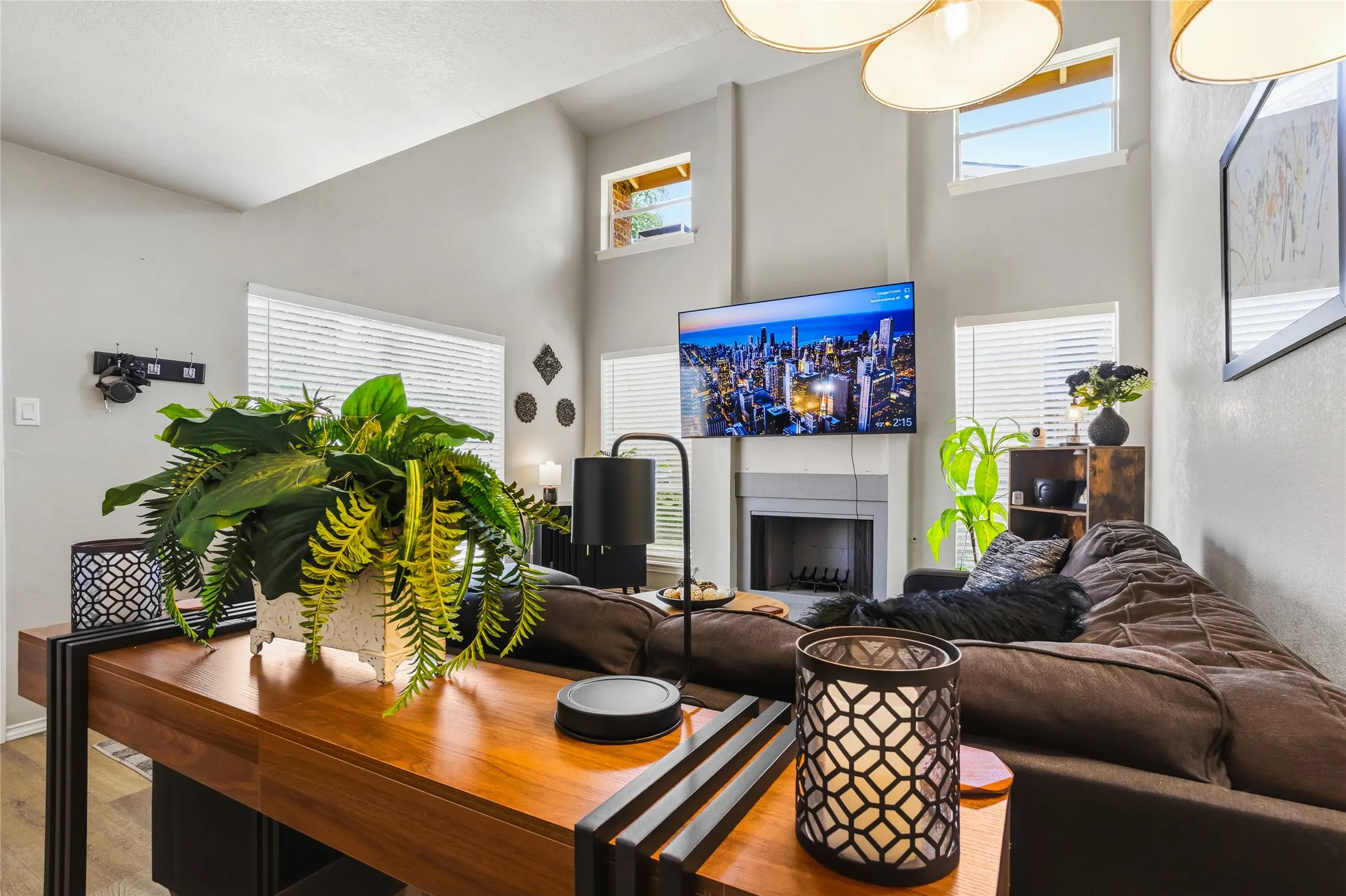 Living area featuring high ceilings, a wall-mounted television, and a fireplace with a stone surround