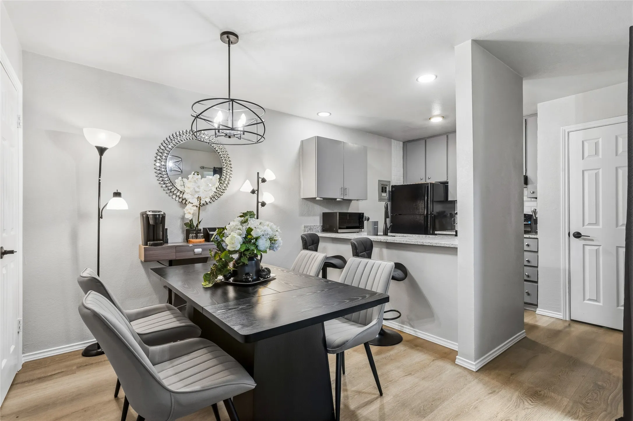 Dining area featuring a contemporary chandelier, wood-finish flooring, and a breakfast bar with stone-finish countertops