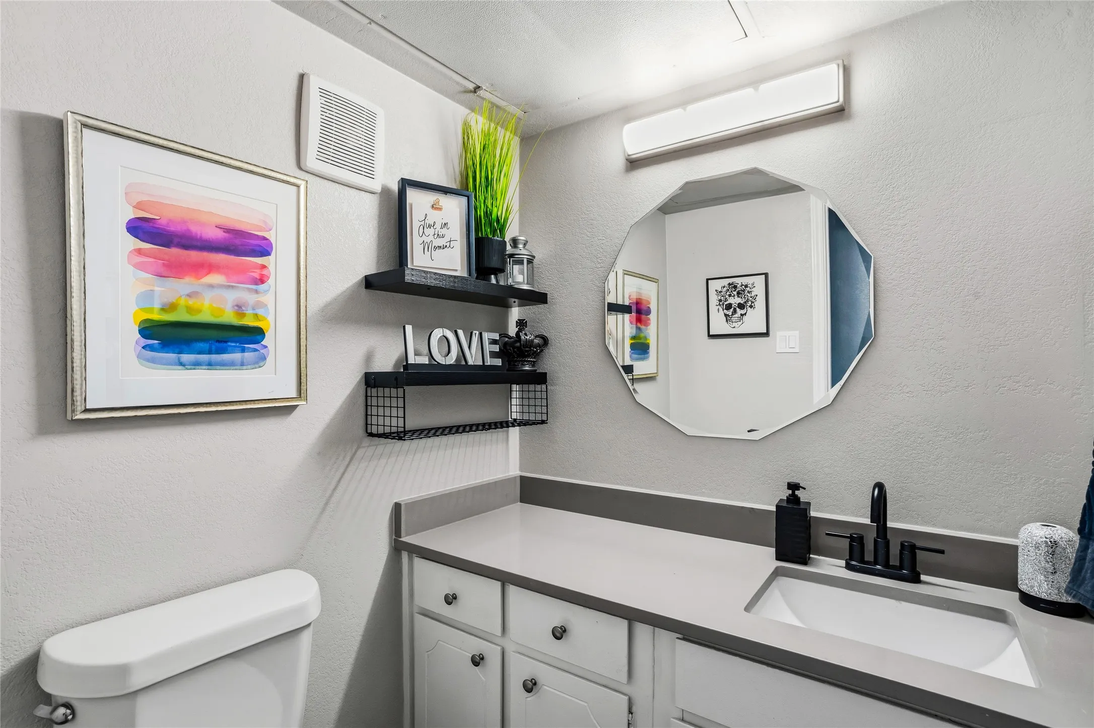 Downstairs guest bath with a vanity area featuring a light gray countertop with an integrated rectangular sink, matte black faucet, and white cabinetry