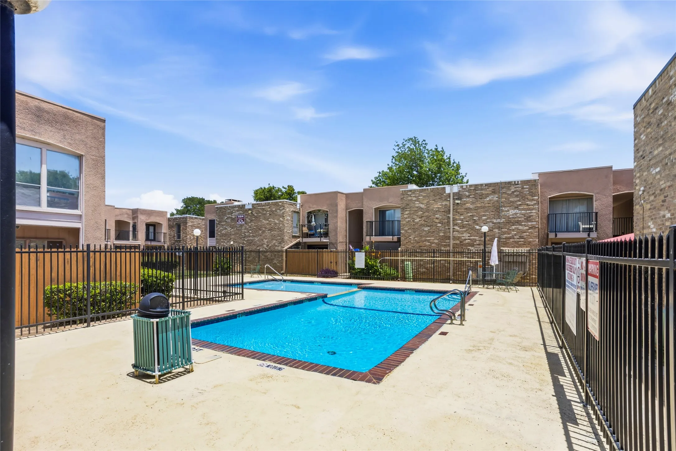 Gated community pool area featuring a rectangular main pool and an attached smaller pool