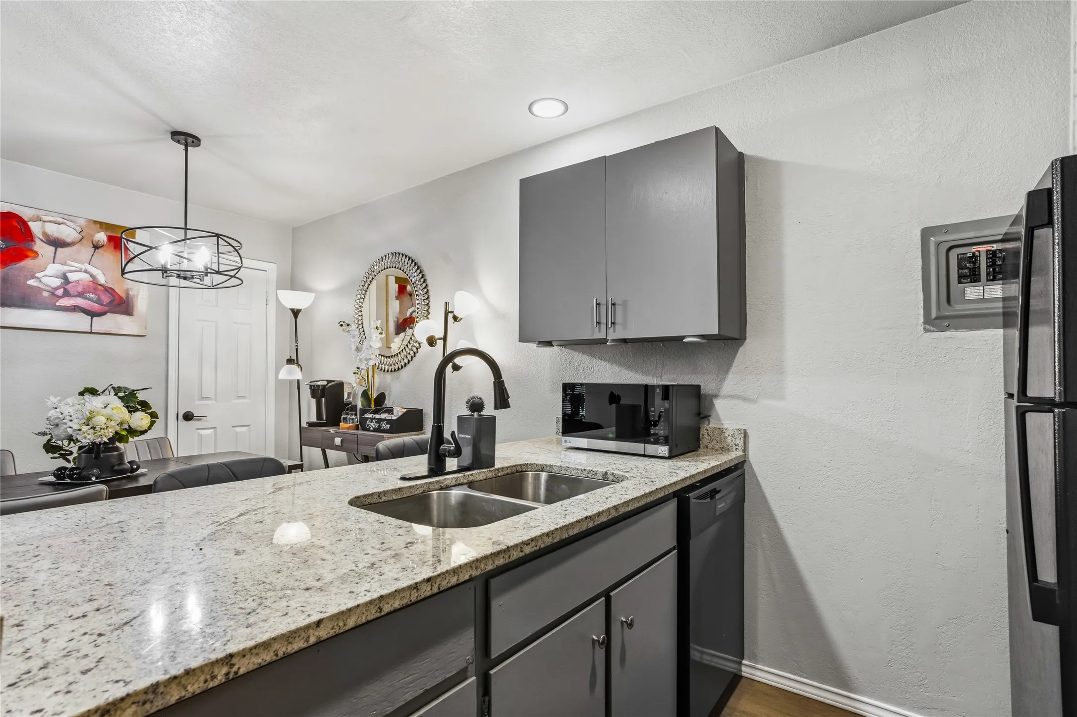 Kitchen featuring granite countertops, a double basin stainless steel sink with a gooseneck faucet, gray cabinetry, and wood-finish​​‌​​​​‌​​‌‌​‌‌​​​‌‌​‌​‌​‌​​​‌​​ flooring