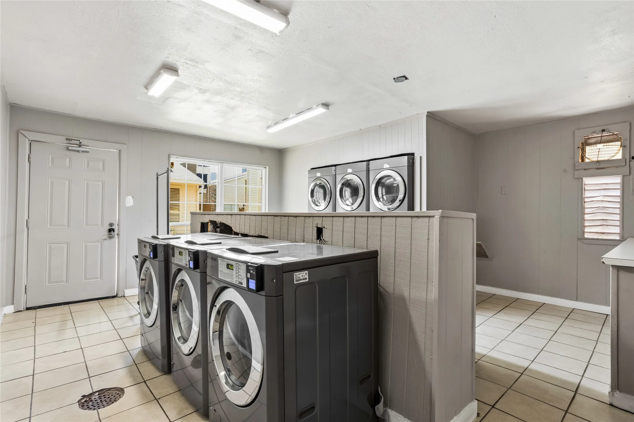 Dedicated On-Site laundry room featuring multiple front-loading washing machines and dryers