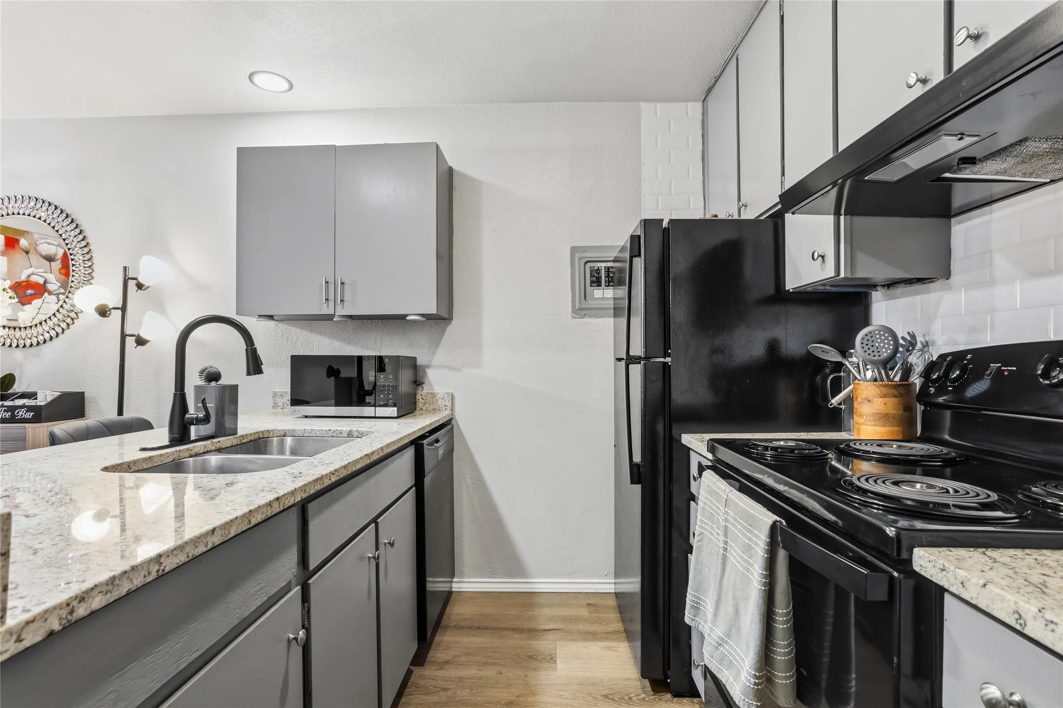 Kitchen featuring black appliances, light-toned granite countertops, and gray cabinetry