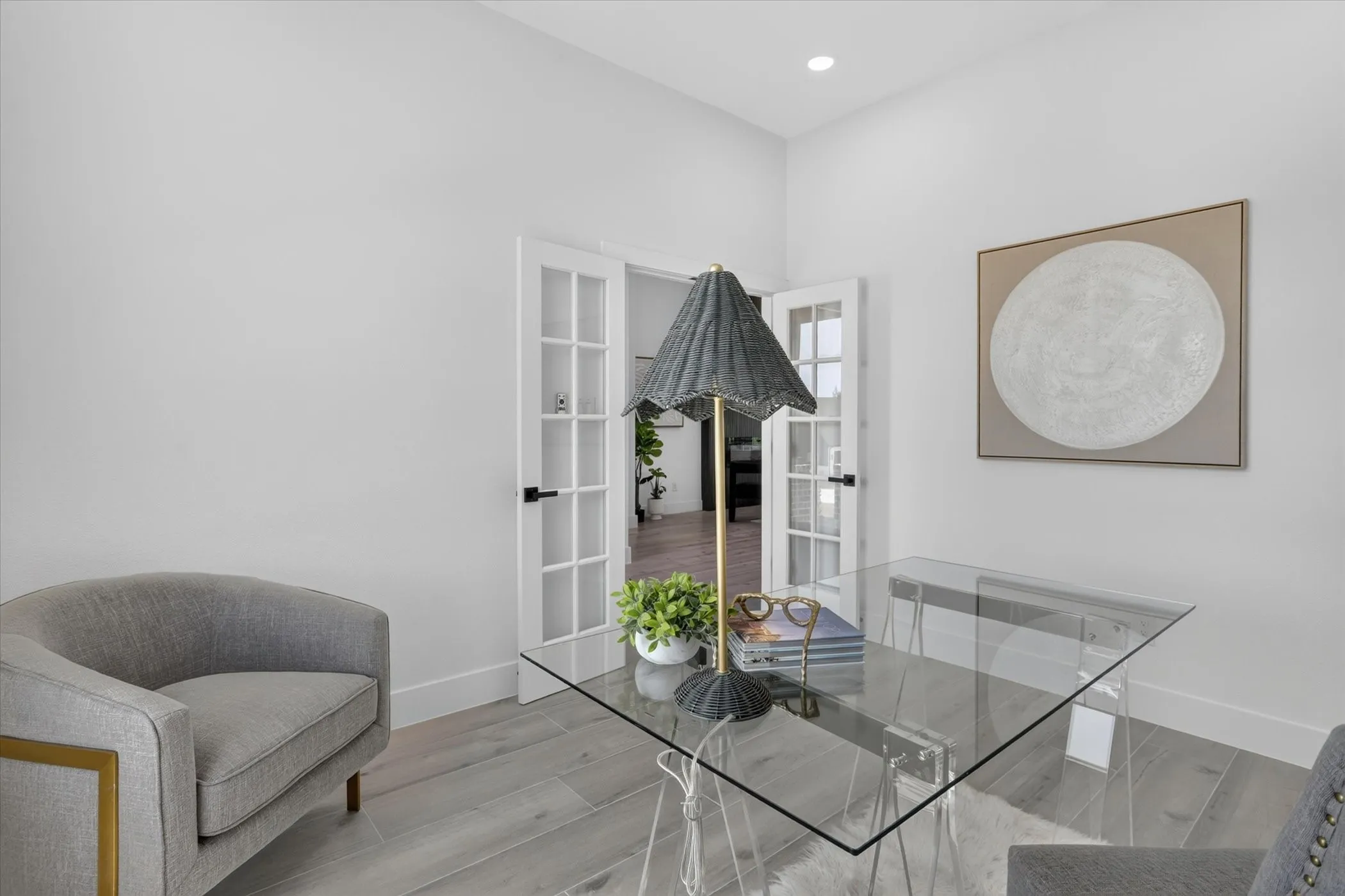 Spacious room featuring light wood-finish flooring, white walls, and elegant French doors with black hardware