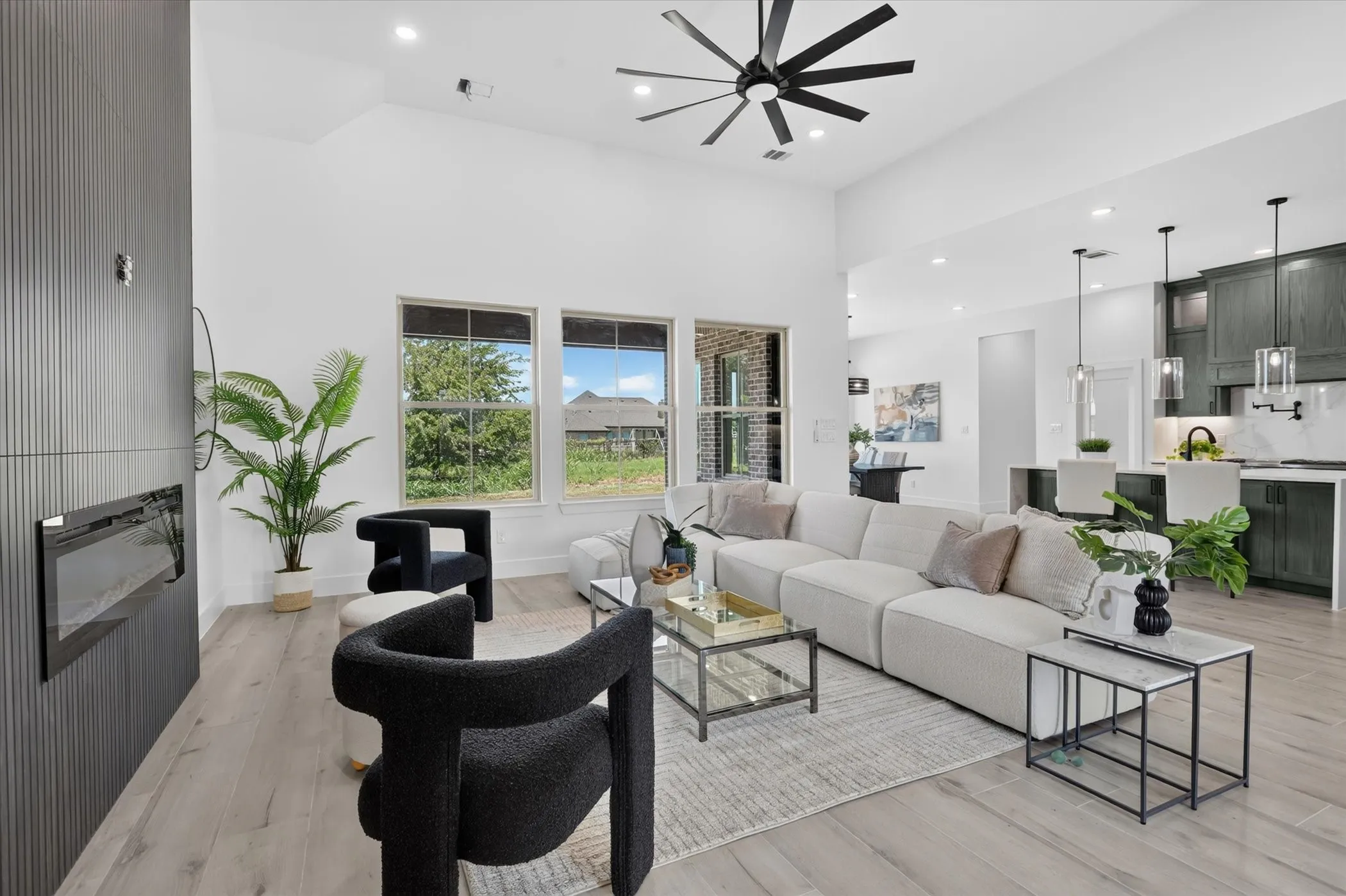 Spacious living area featuring a vaulted ceiling with a modern ceiling fan, recessed lighting, and light wood-finish flooring