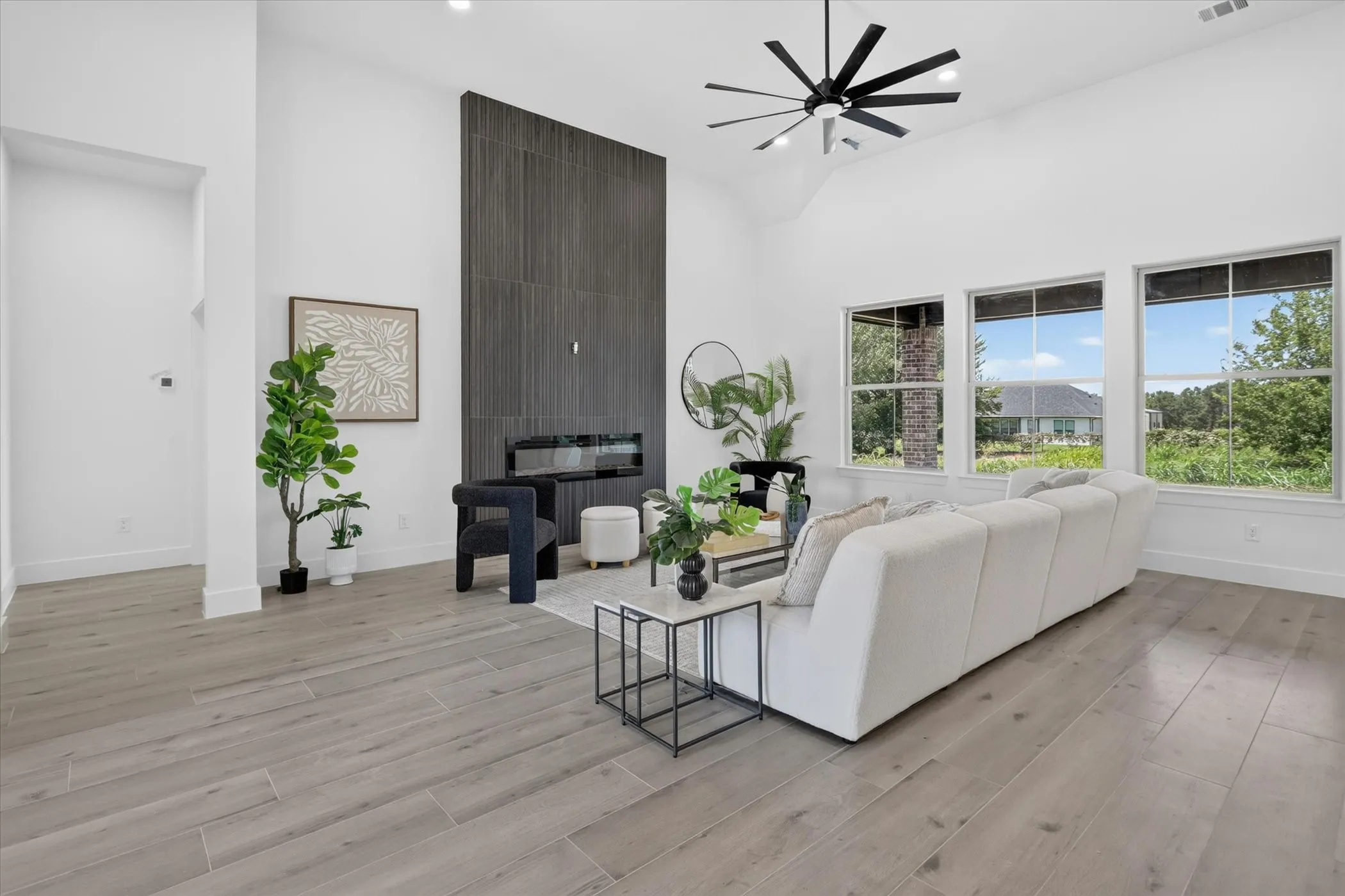 Spacious living area featuring a vaulted ceiling, wood-finish flooring, and a modern fireplace with a dark tile surround