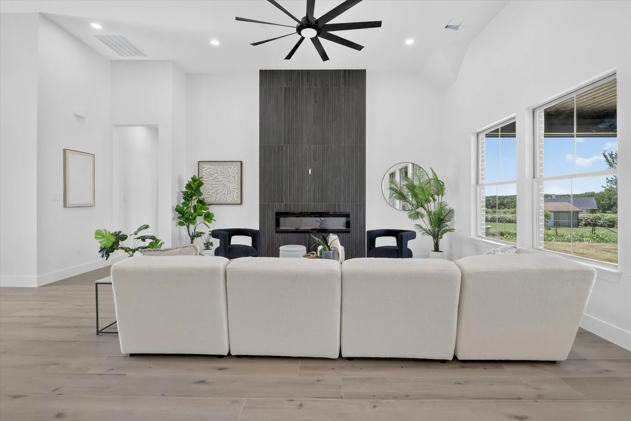 Living area featuring a floor-to-ceiling fireplace with dark tile surround, integrated linear firebox, and a black ceiling fan