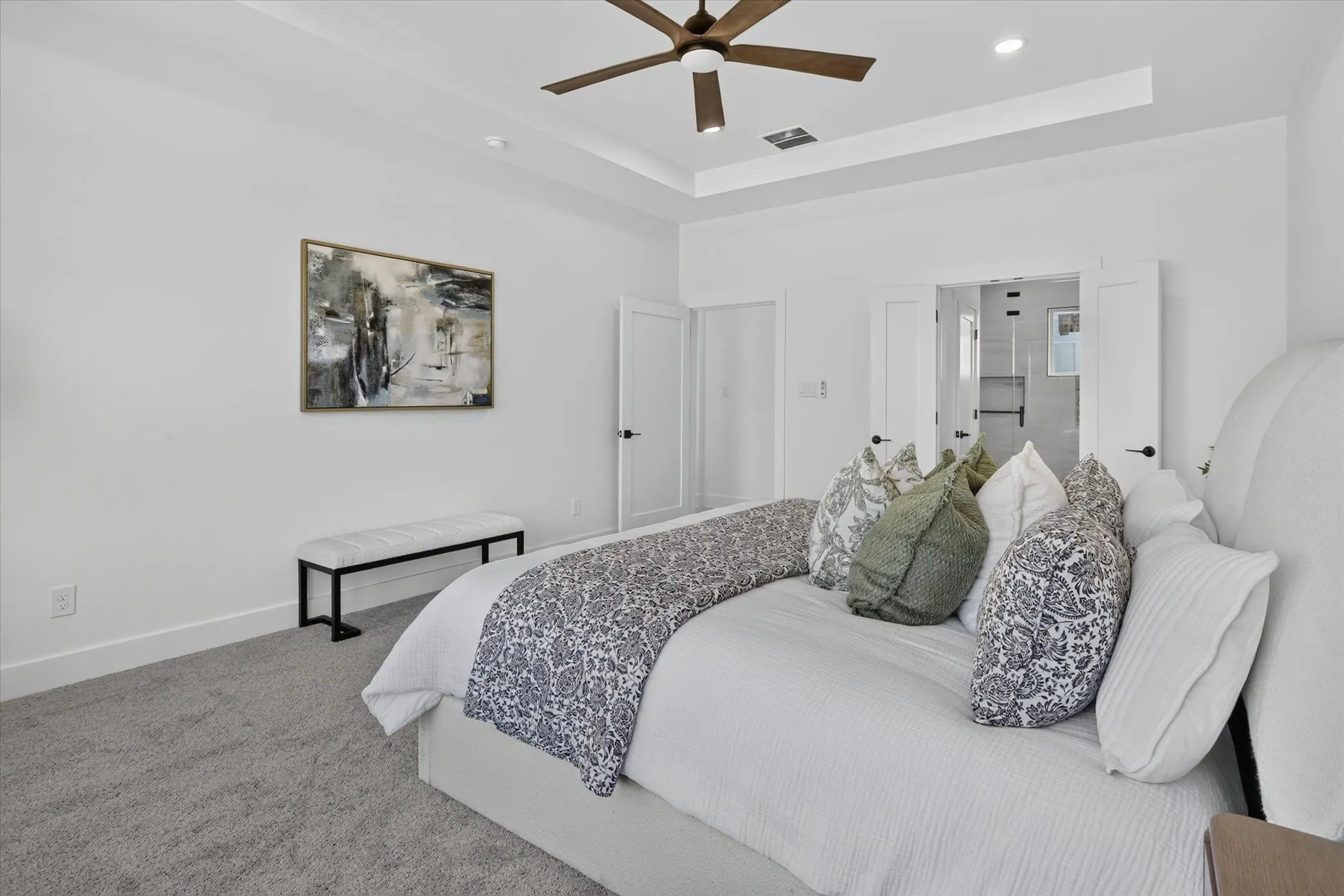 Carpeted room featuring a ceiling fan with integrated lighting, tray ceiling, and white double doors