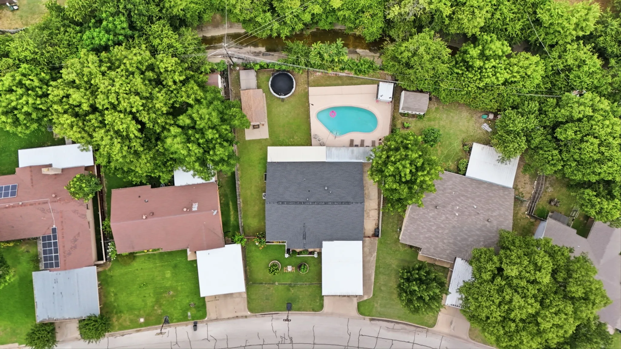 Aerial perspective of a property featuring a central residence with a dark shingle roof