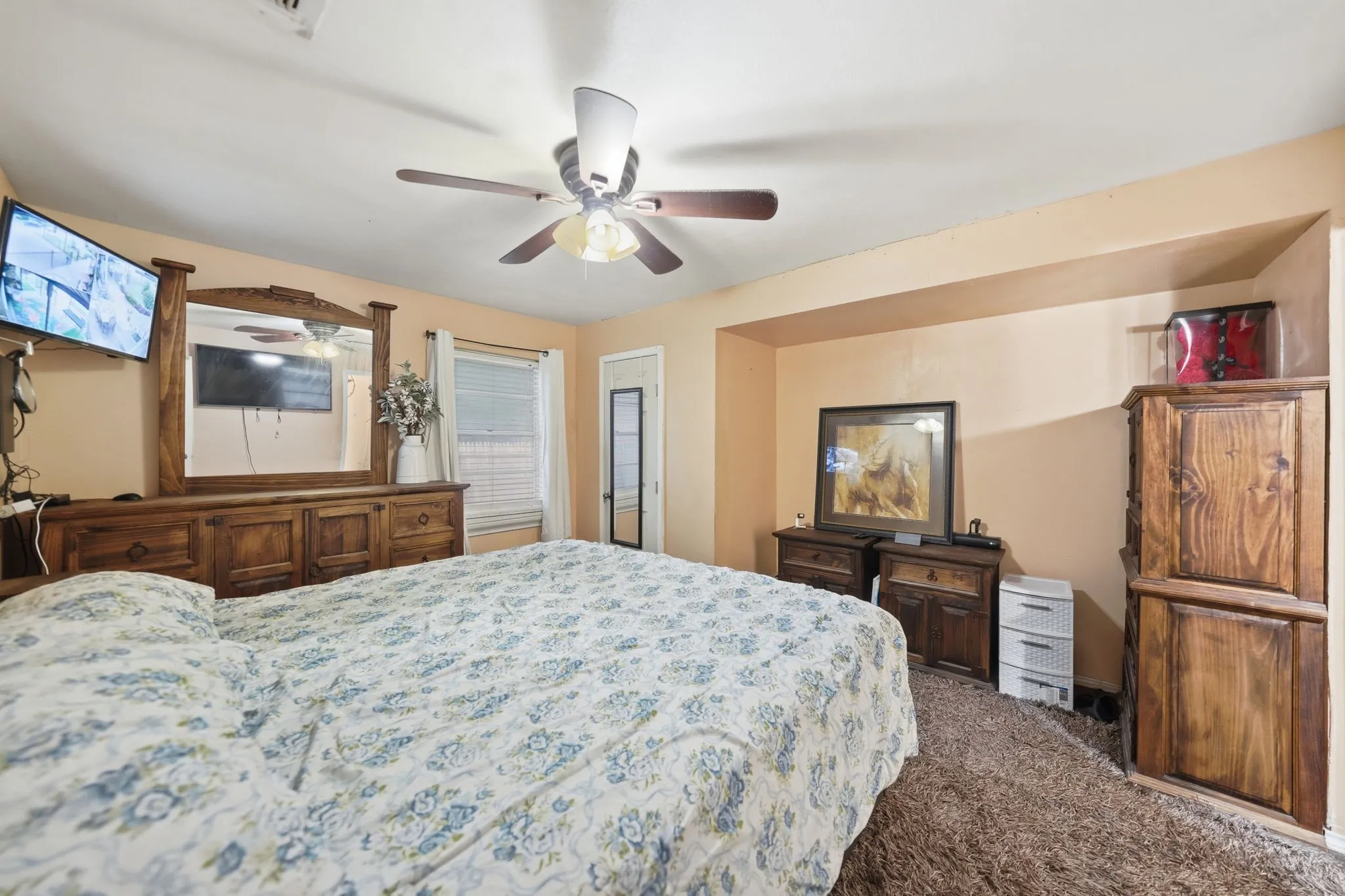 Carpeted bedroom featuring a ceiling fan, a window with blinds, and an alcove