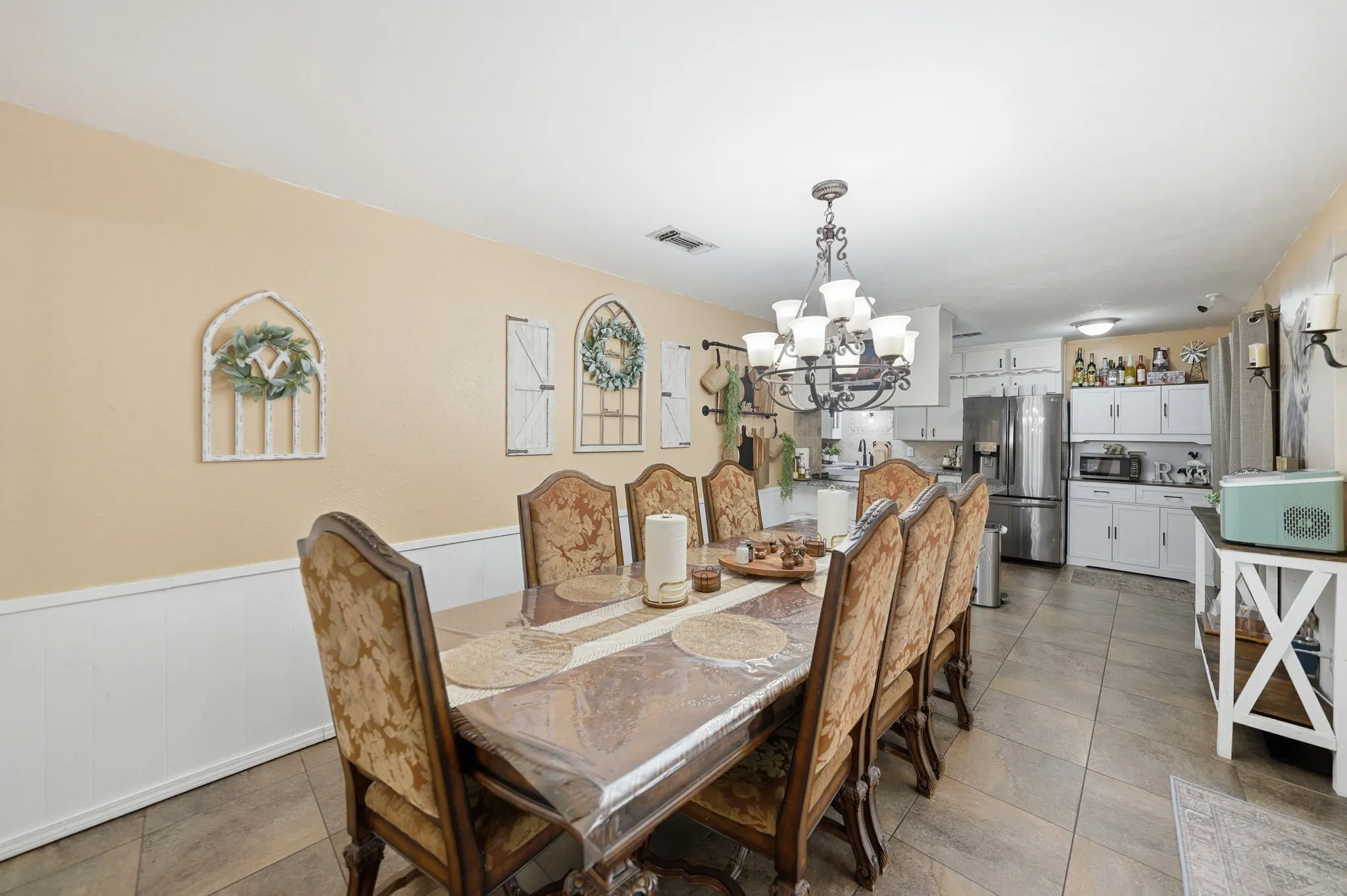 Dining area featuring a decorative chandelier, wainscoting, and tile flooring