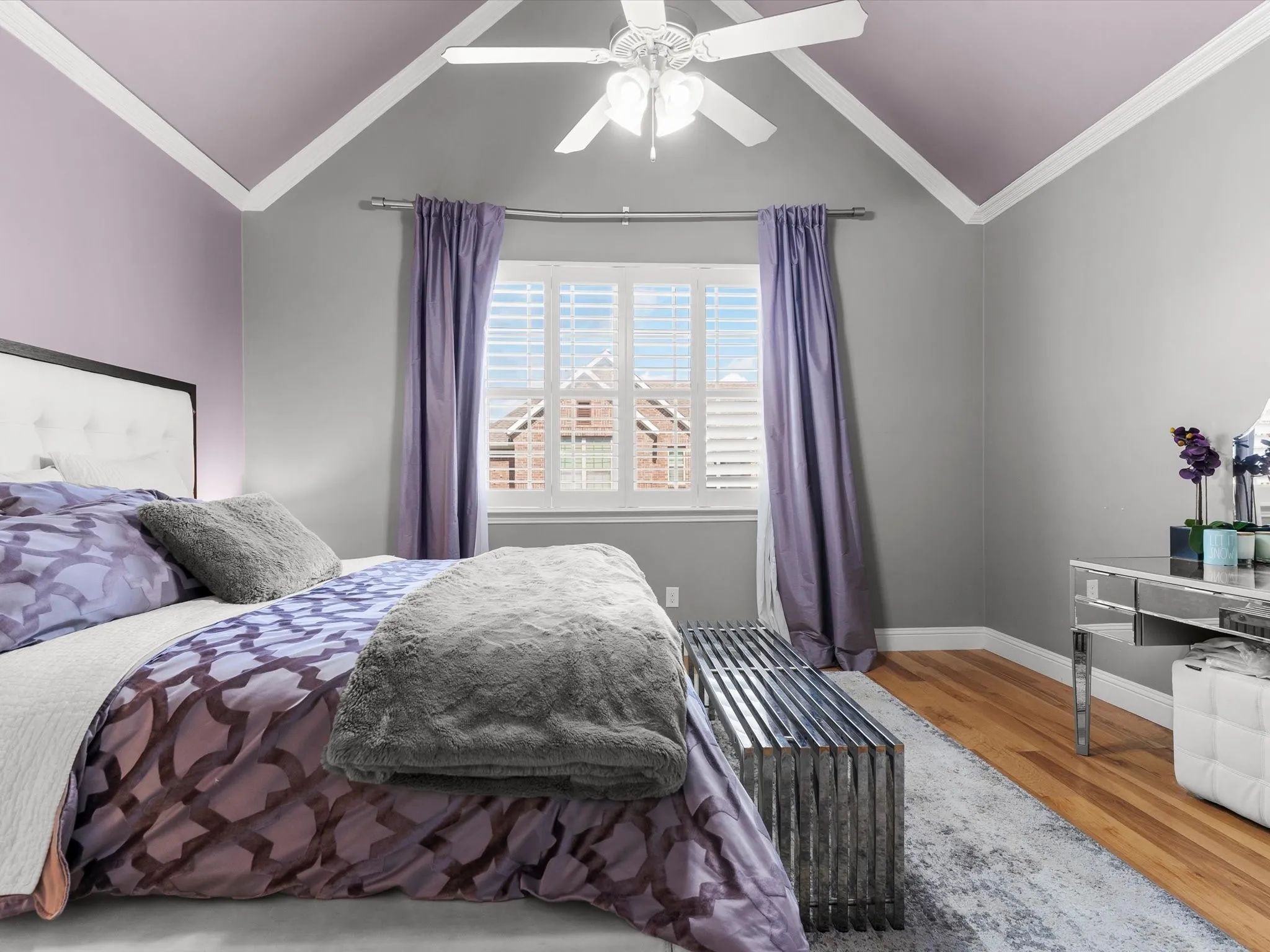Room featuring vaulted ceilings with crown molding, hardwood flooring, and a ceiling fan with integrated lighting