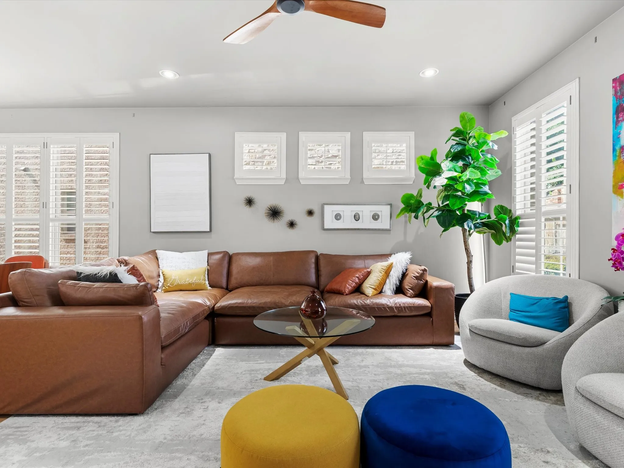 Spacious living area featuring a ceiling fan with wood-finish blades, recessed lighting, and plantation shutters