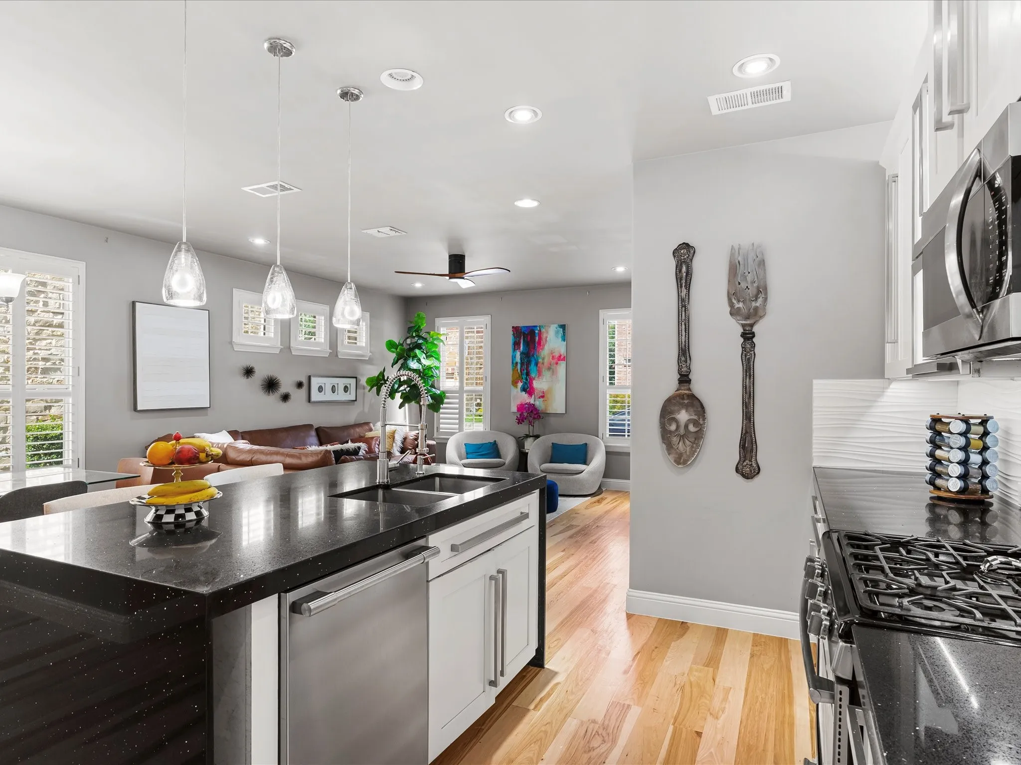 Kitchen featuring a black speckled countertop island with an undermount sink and stainless steel dishwasher